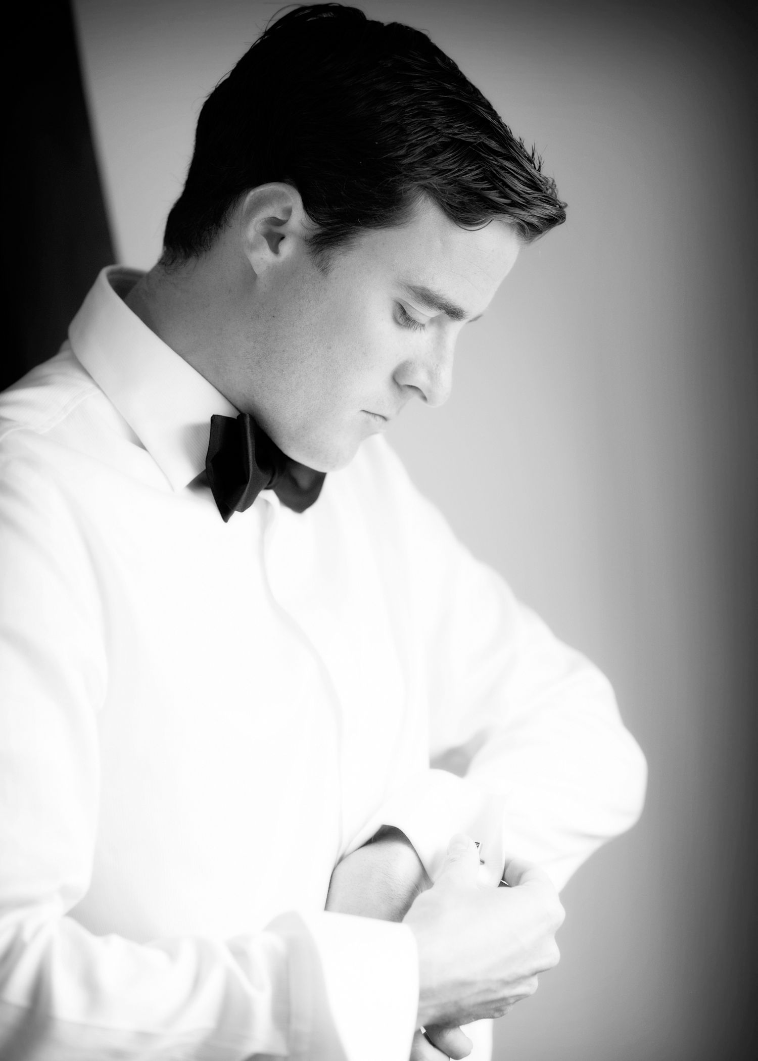 A figure in a white button-down shirt is shown in profile view against a dark background in an artistic black and white portrait.