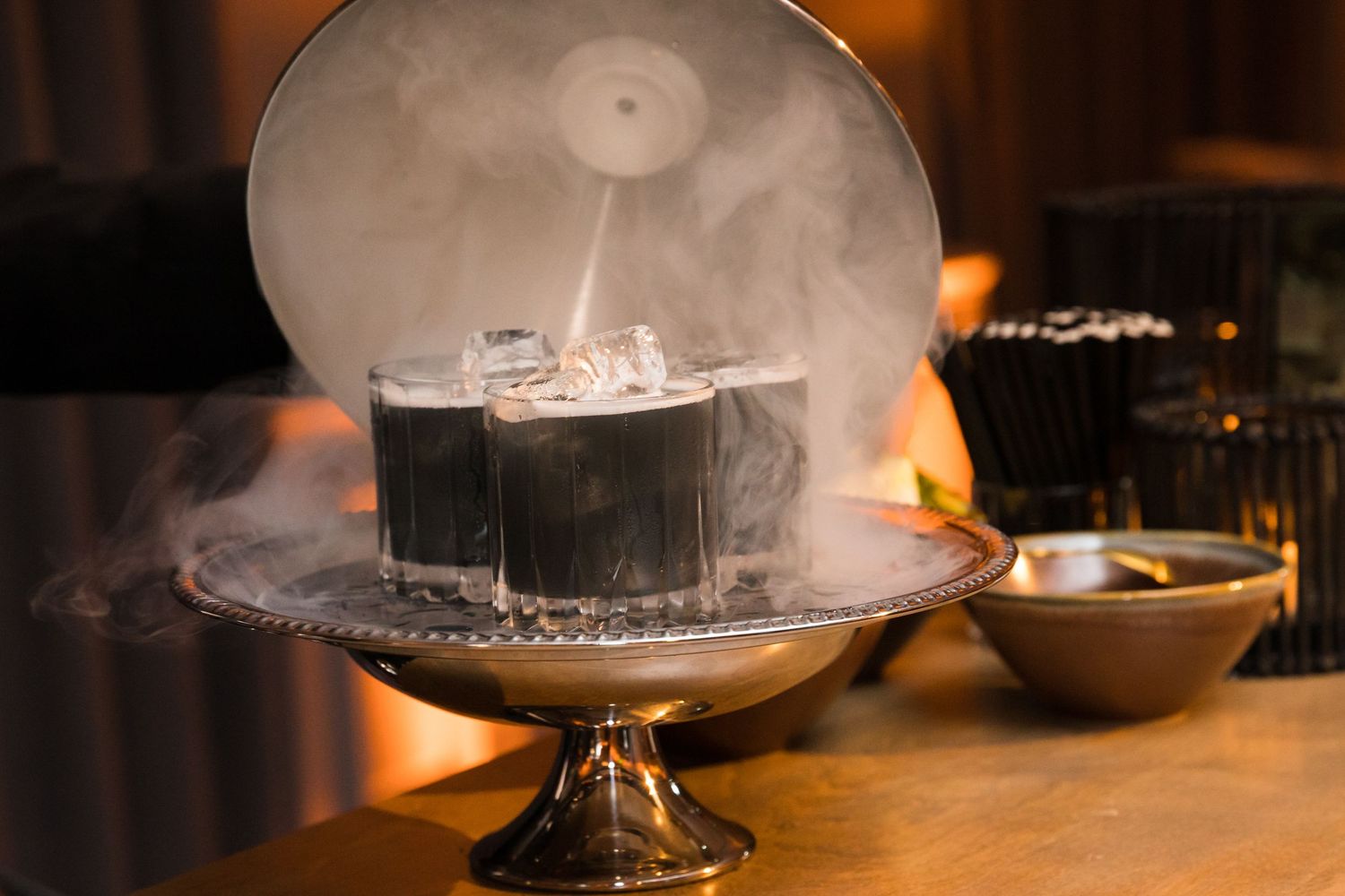 Dramatic presentation of smoking cocktails served on an elegant silver platter.