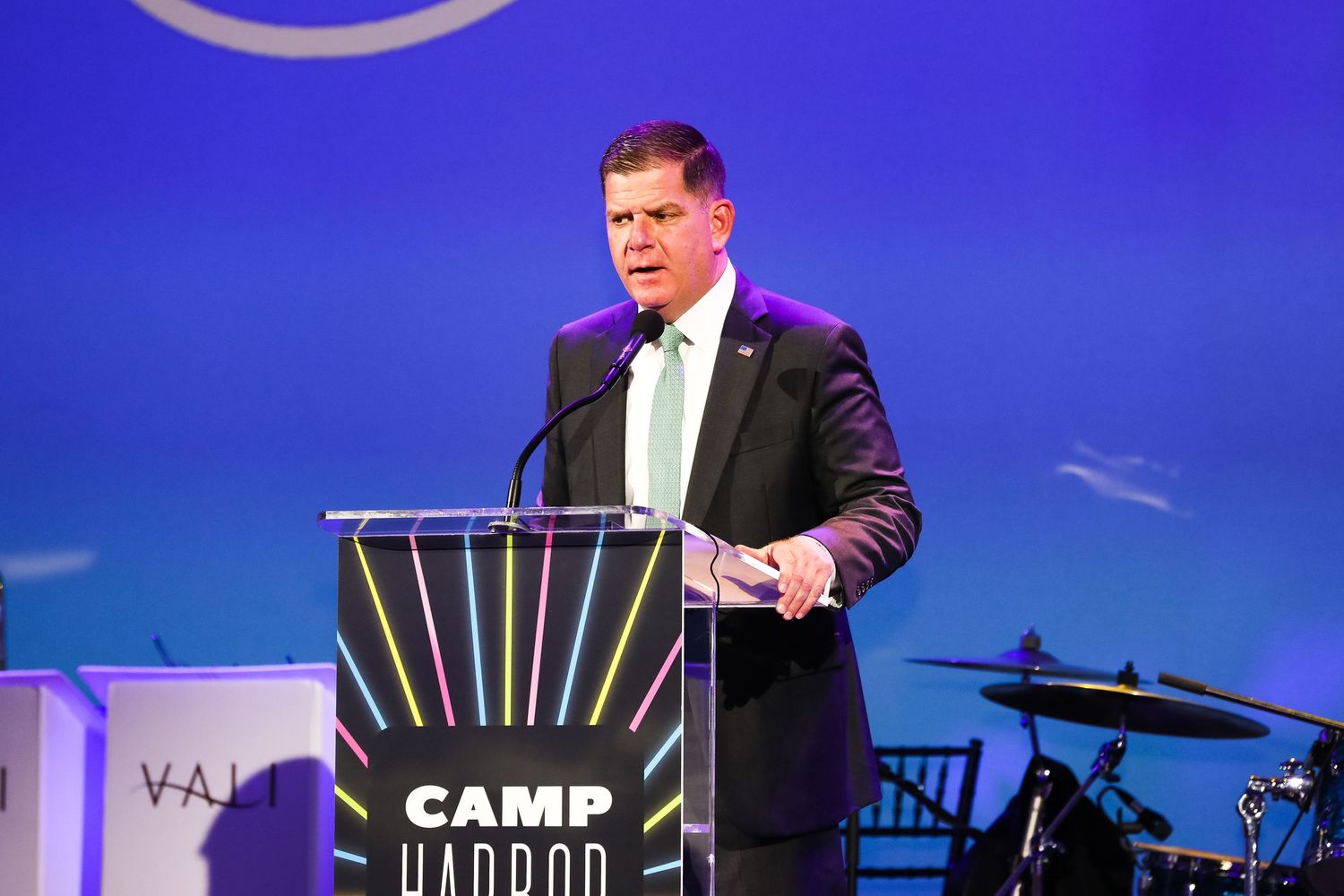 Speaker presenting at Camp Harbor conference podium with blue backdrop.