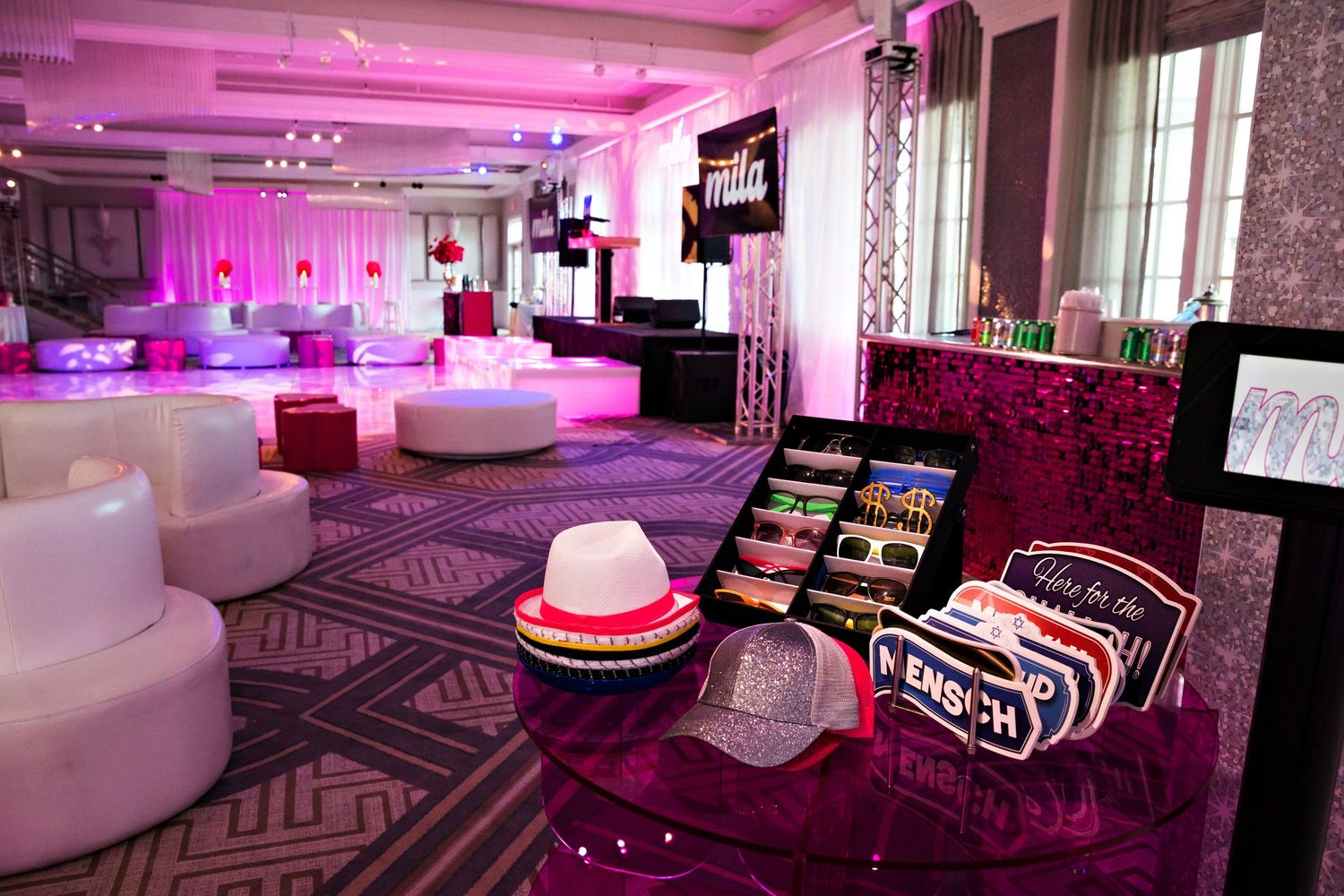Modern party venue with pink lighting, white lounge furniture and geometric patterns.