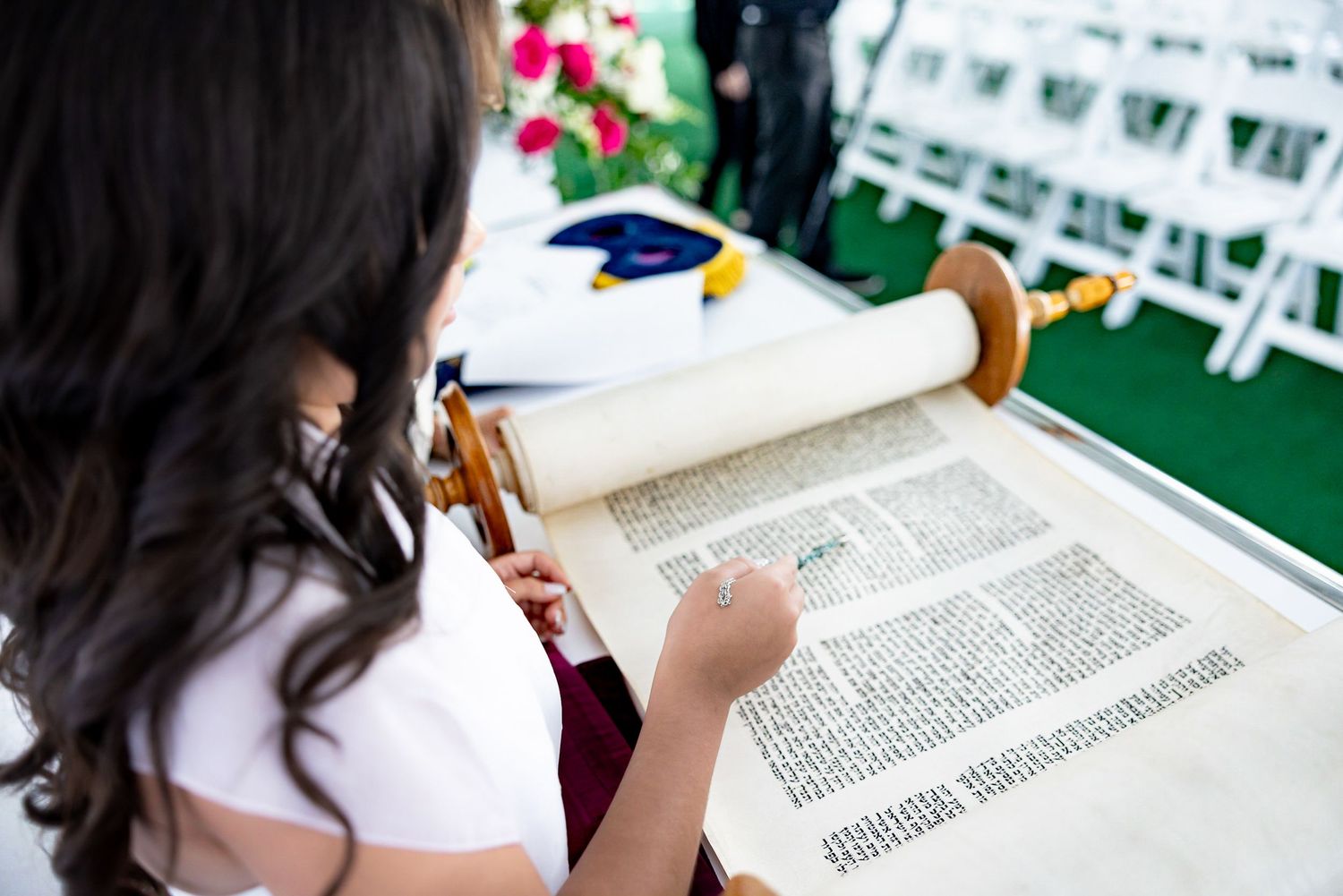 An overhead view of someone reading from a traditional religious scroll outdoors.