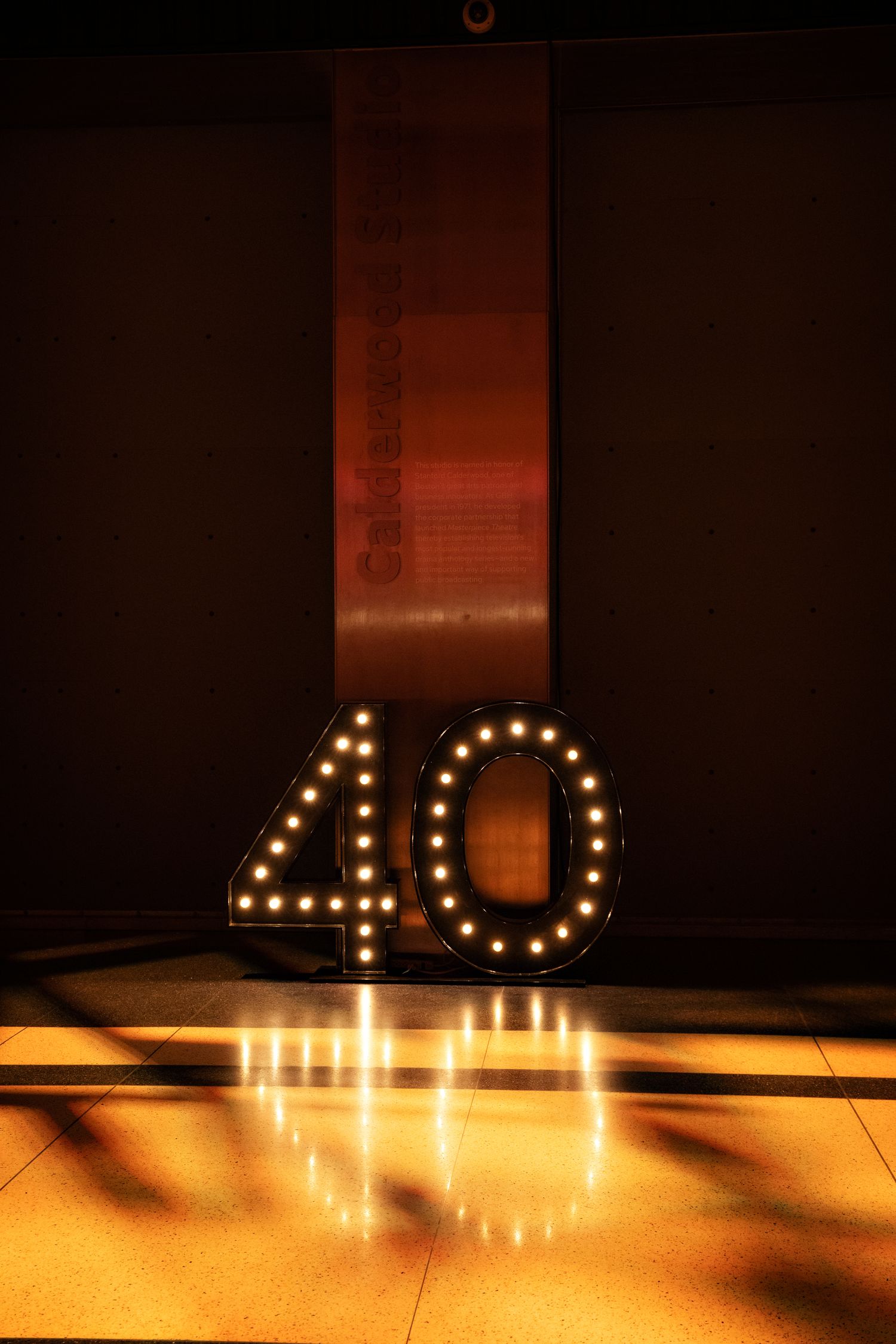 Illuminated number 40 sign casting reflections on a polished floor in dramatic lighting.