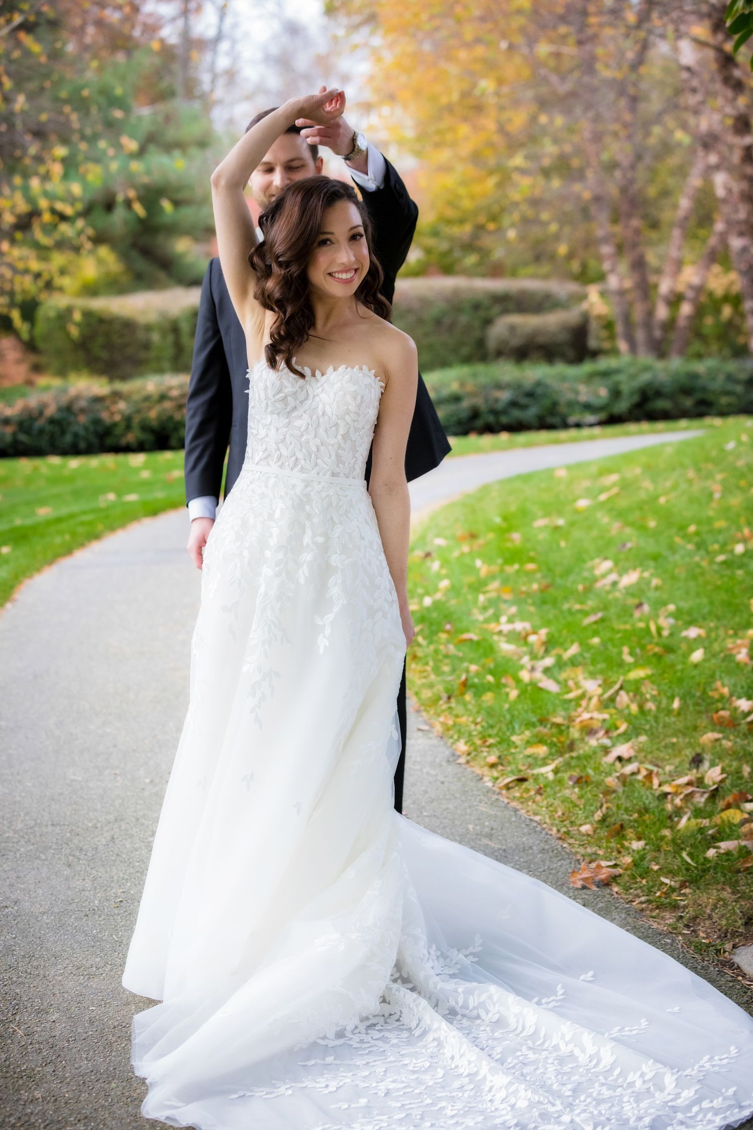 A romantic fall wedding photoshoot featuring a flowing white gown against colorful autumn foliage in a park setting.