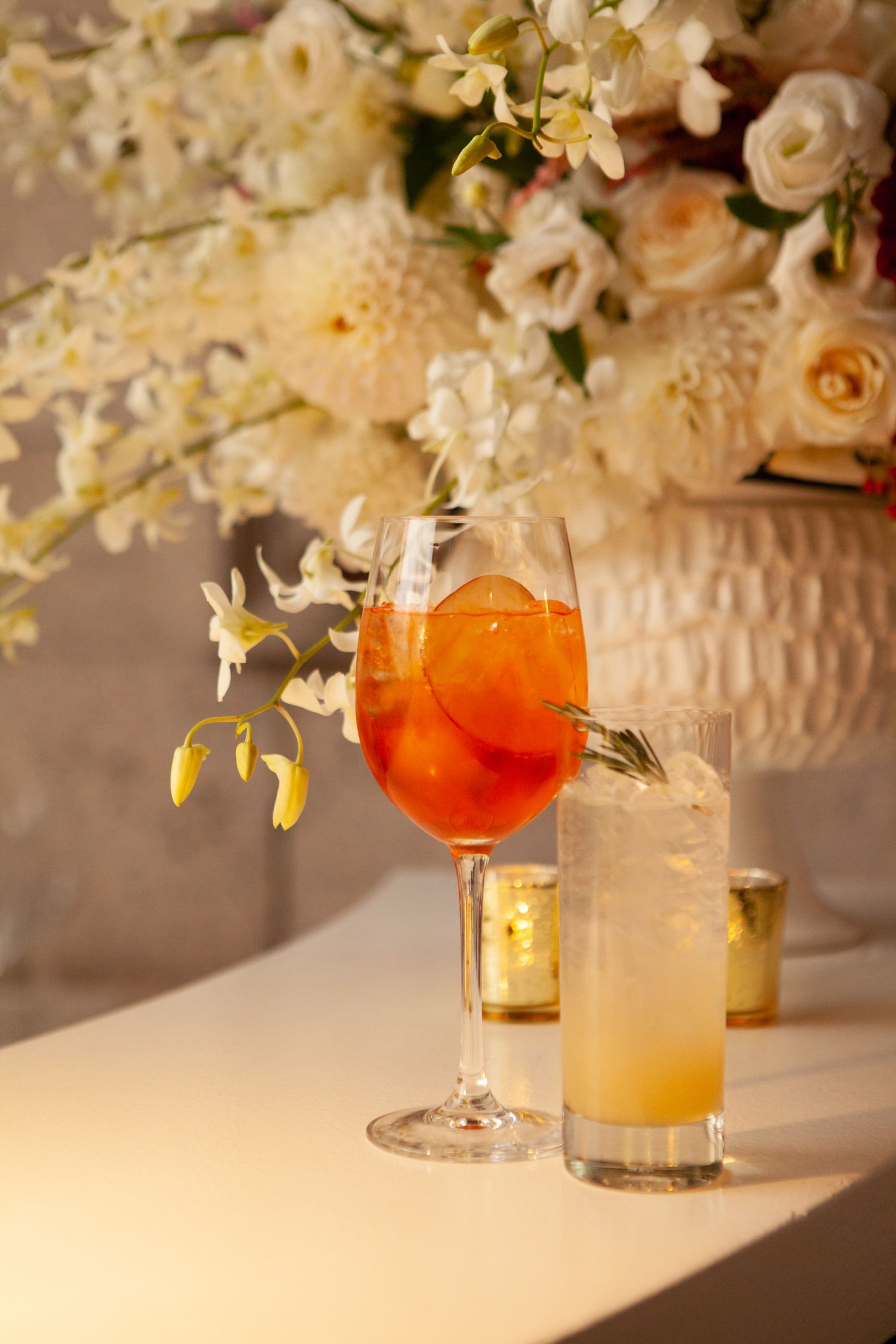 Elegant cocktails served alongside white floral arrangements with romantic candlelight.