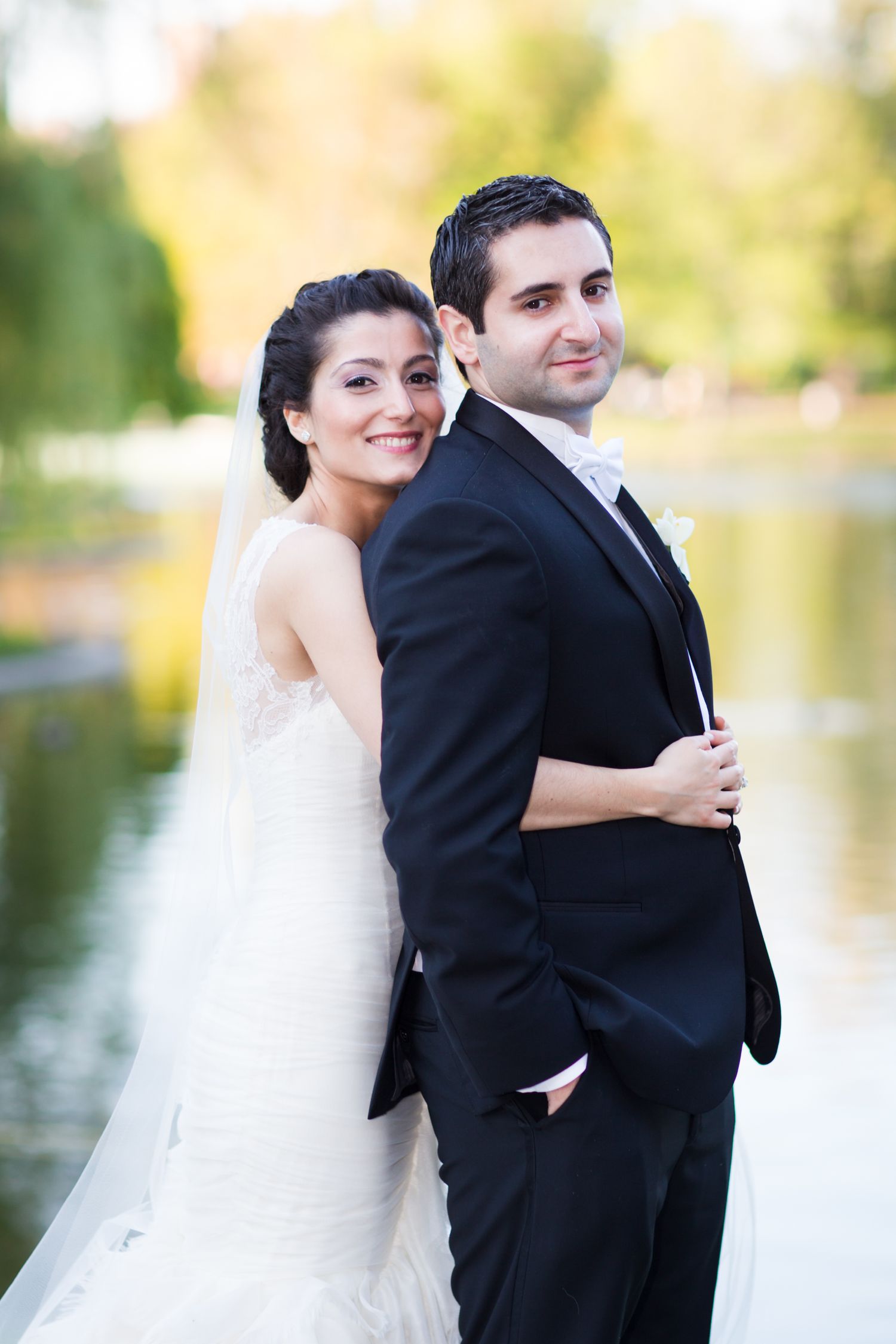 A bride and groom share romantic moments by a lake during their wedding photo session in the Boston Public Gardens