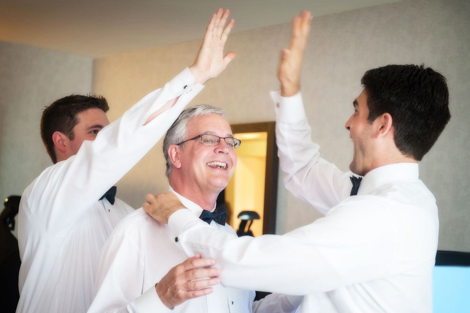 A series of people in white dress shirts with raised hands high-fiving each other in an office setting.