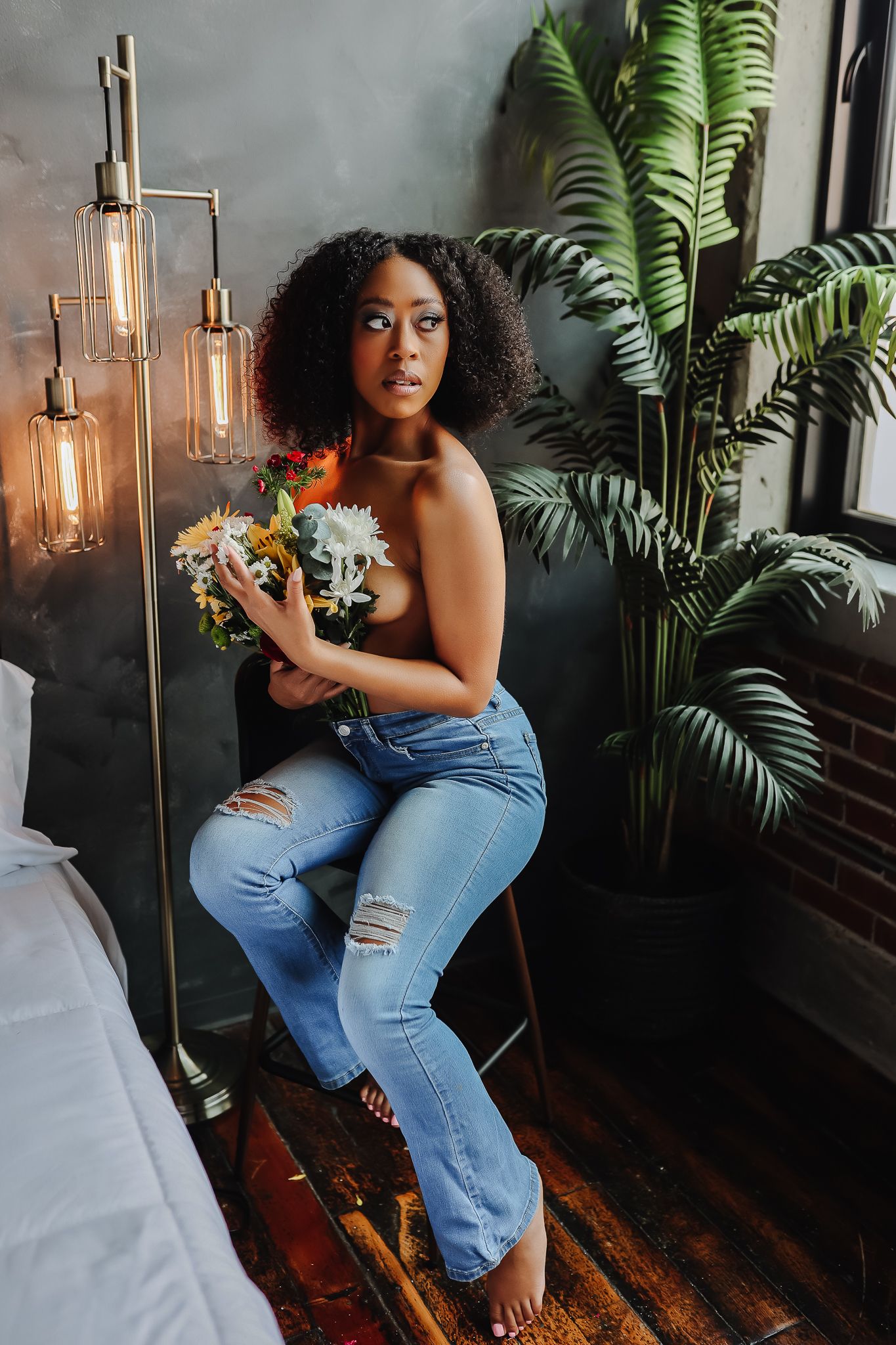 Natural light portrait with houseplants and bouquet in modern industrial setting.