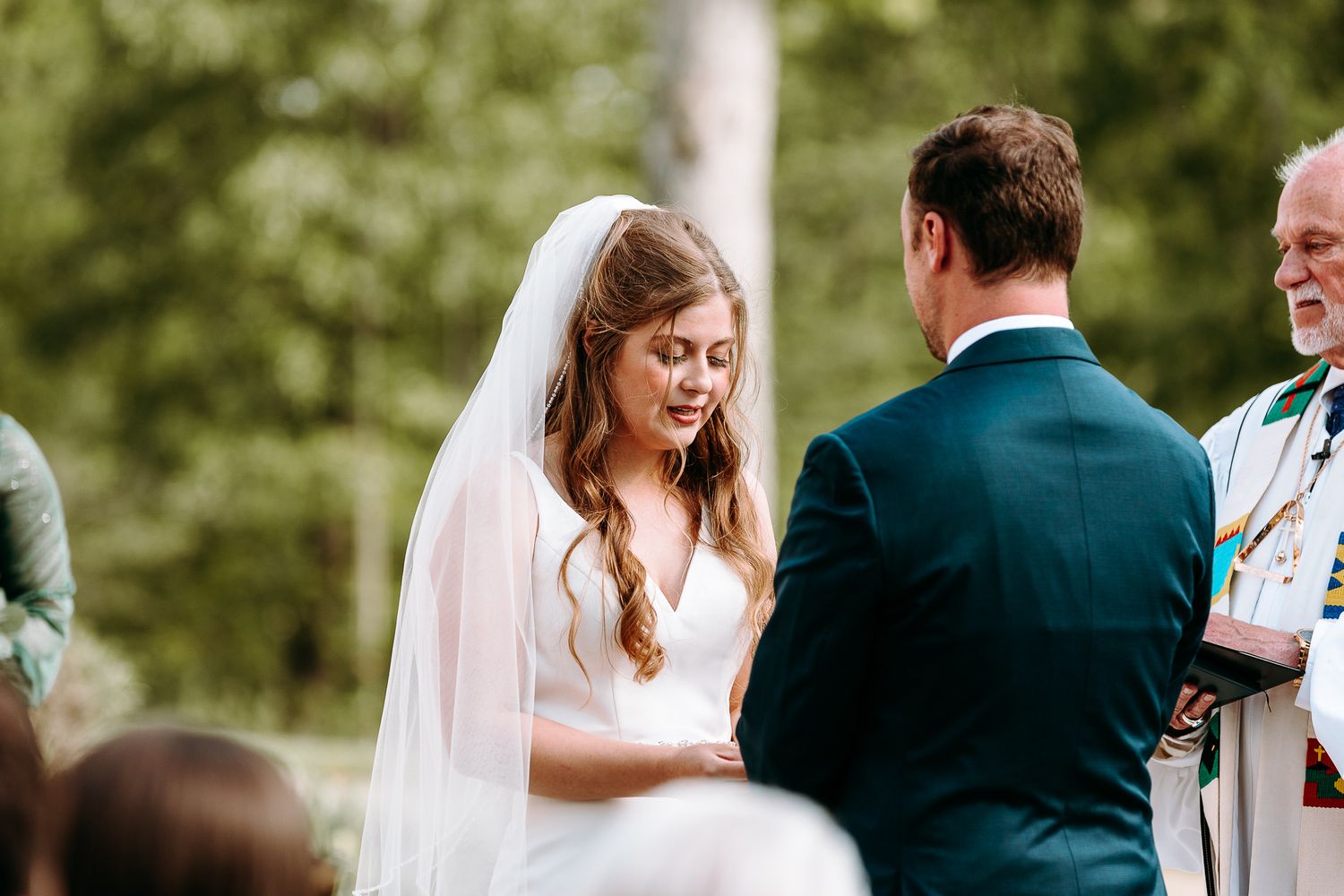 Wedding ceremony in progress as bride laughs joyfully during exchange of vows.