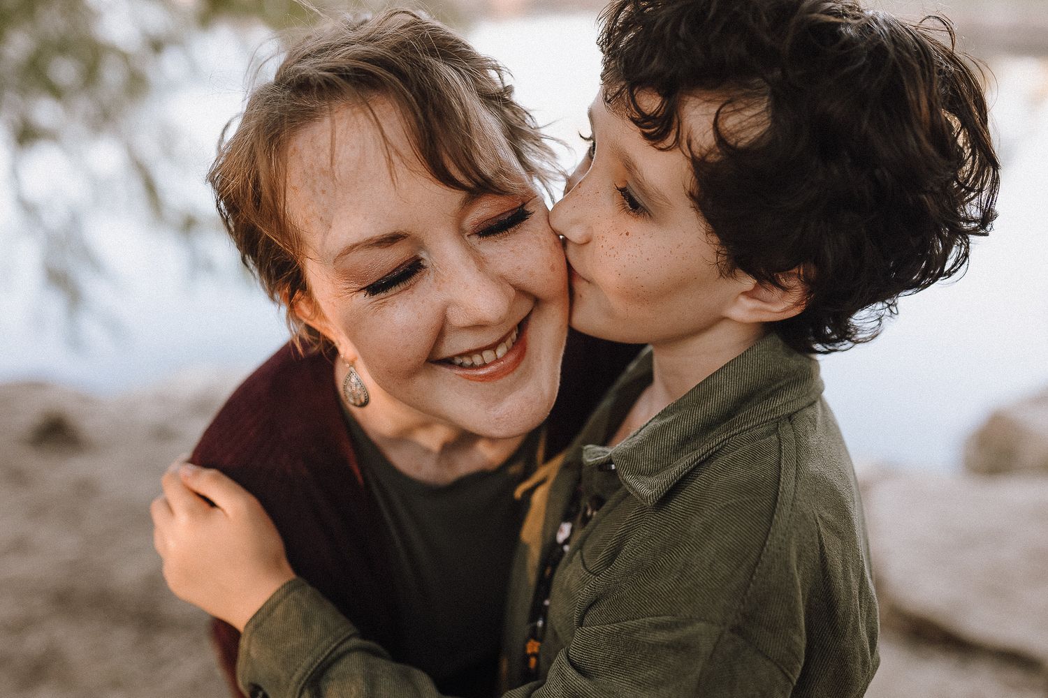 Candid moment of affection captured between parent and child outdoors.