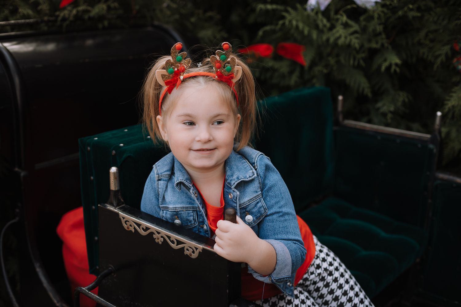 A festive winter portrait showing seasonal red and green hairbows with a denim jacket and plaid skirt outfit.