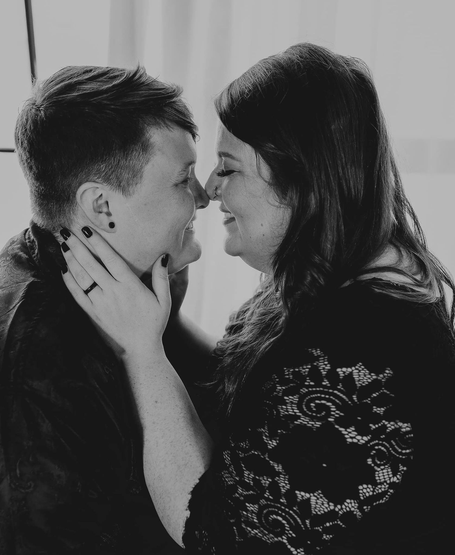 An intimate black and white portrait of a couple sharing a tender moment.