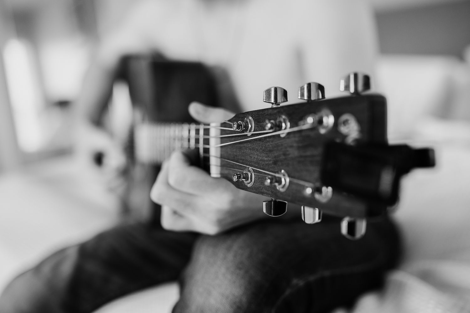 Close-up black and white detail of hands holding a guitar headstock.