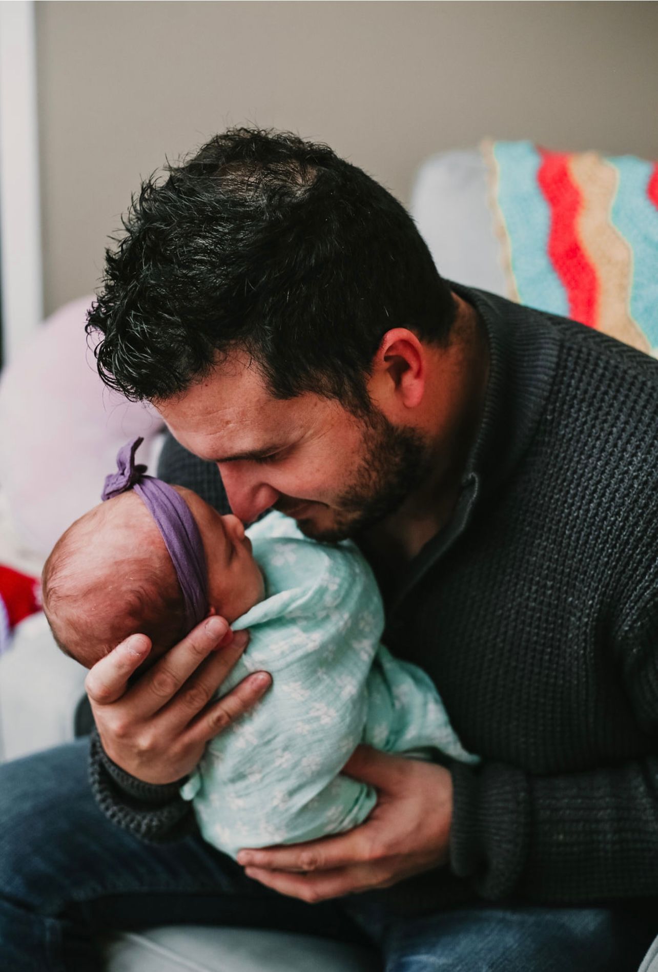 A tender moment between parent and newborn captured in intimate portrait style.