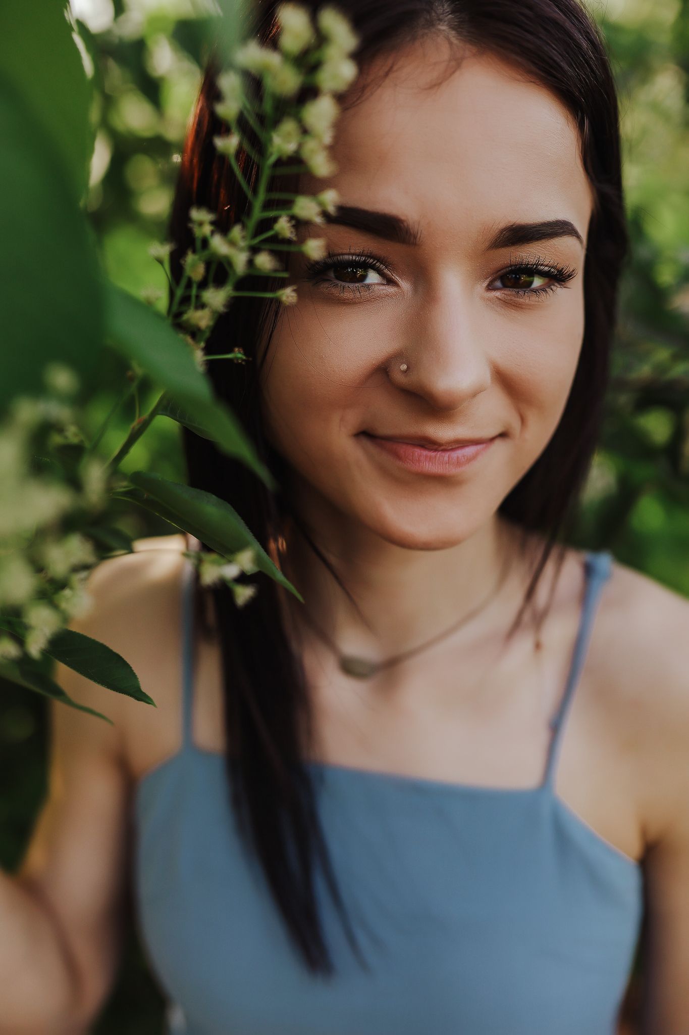 A summer portrait in natural light with green foliage framing the composition.