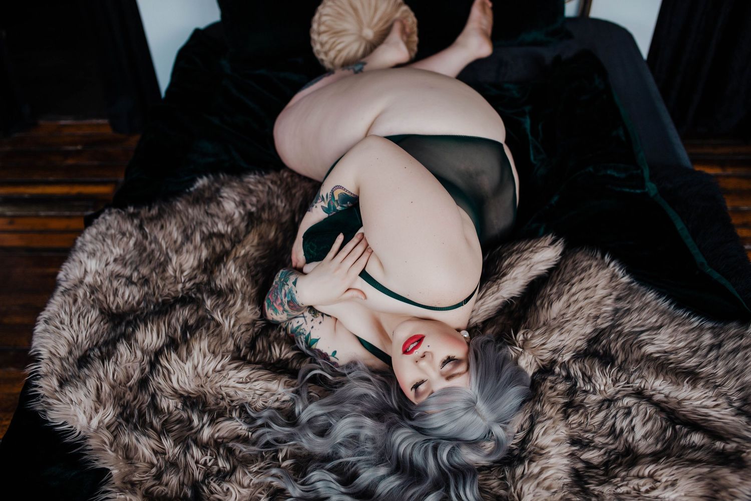 Artistic boudoir photo with vintage fur and sunglasses in moody lighting.