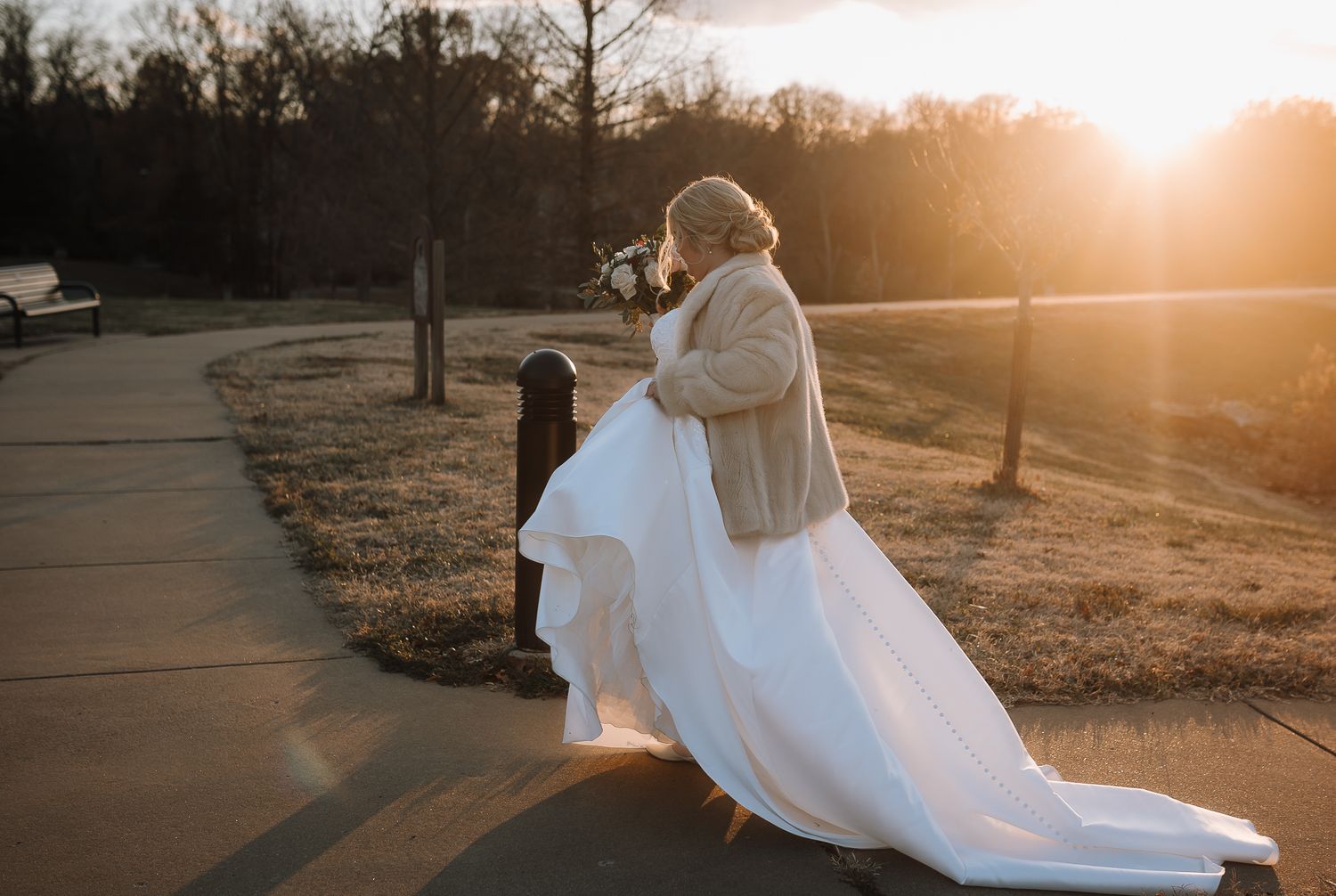 Bride in white dress and beige sweater twirling during sunset photo session.