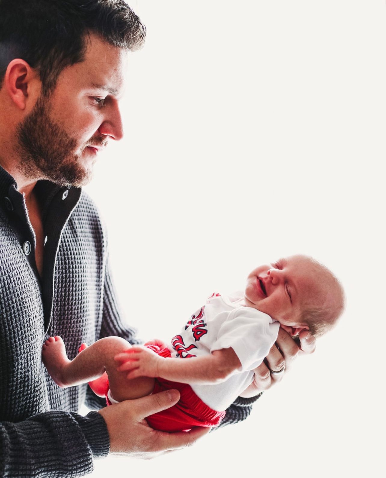 A tender moment captured between a caregiver and crying infant in white clothing.