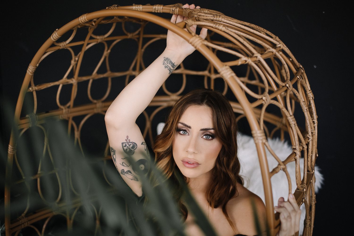 Artistic portrait of woman posing in woven hanging chair.