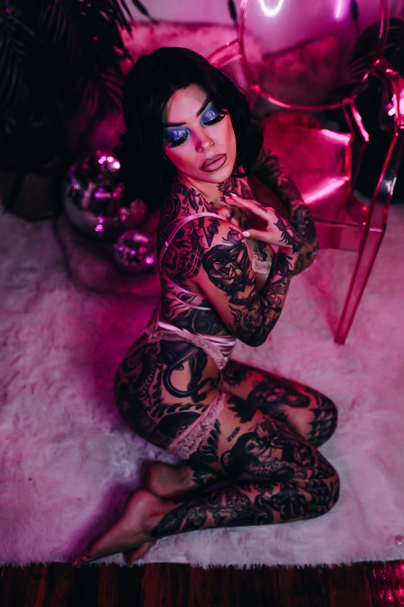 Artistic portrait with pink neon lighting and full body tattoo art.