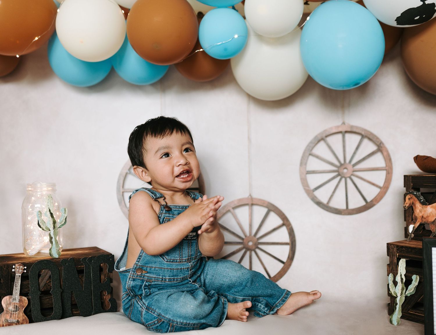 Western-themed party setup with wagon wheel decorations and balloon garland.