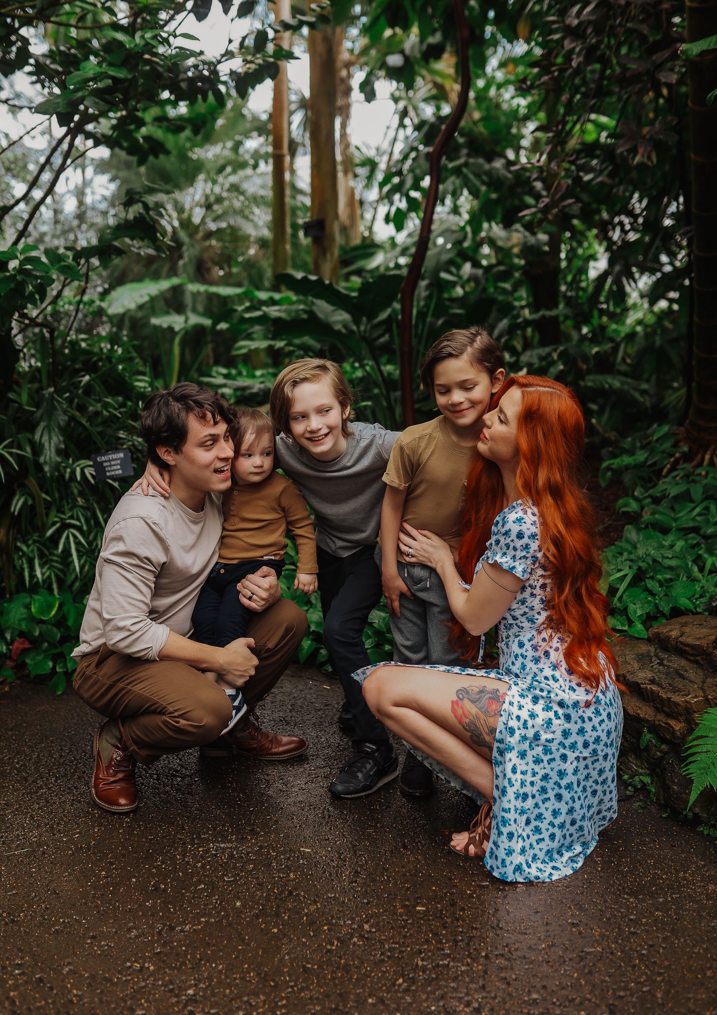 Family portrait in lush green forest setting on dirt path.