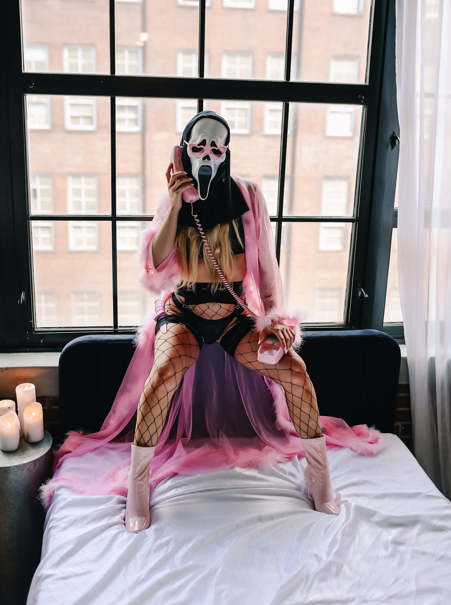 Stylized horror costume photo with person in ghost mask and pink robe on bed.