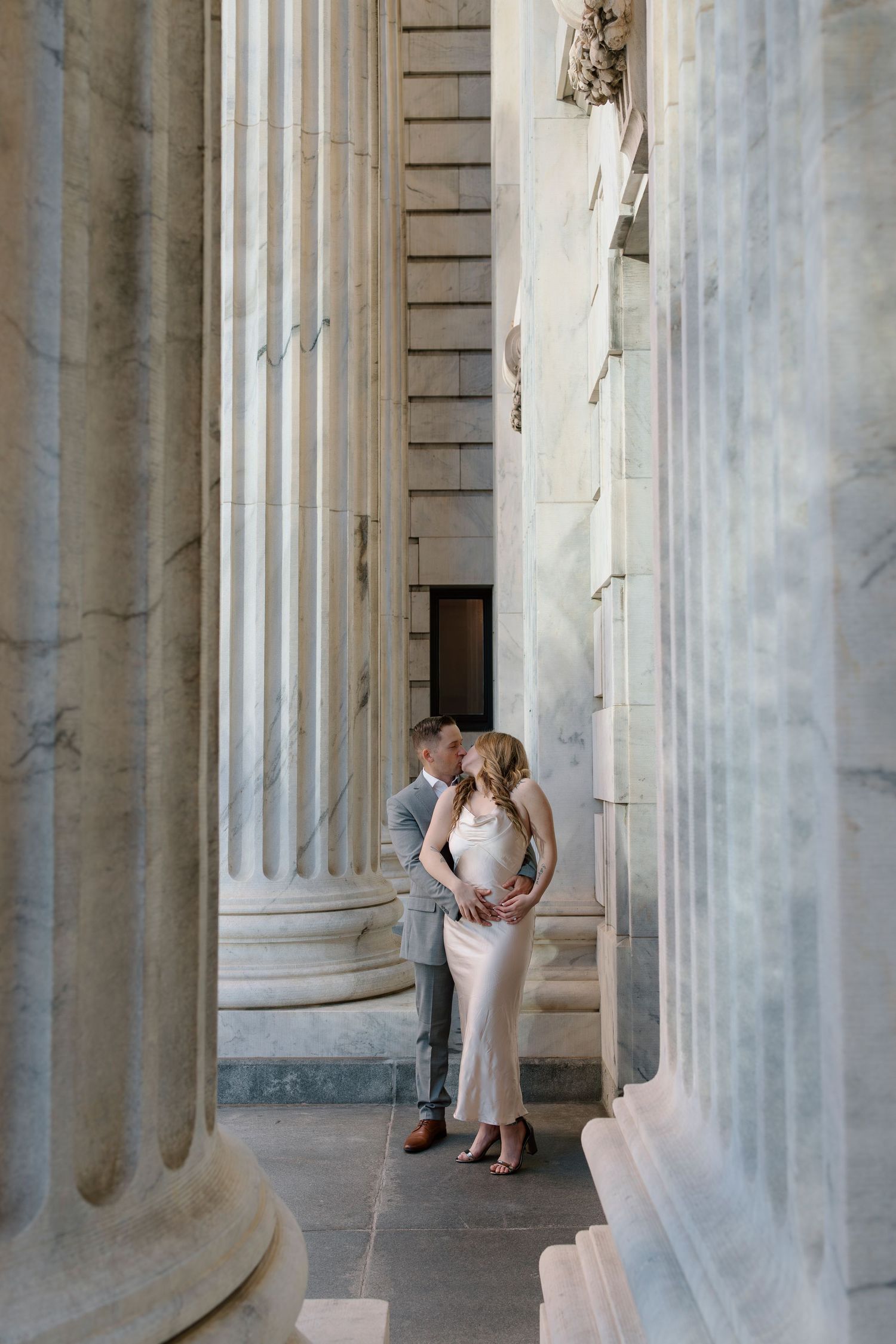 A romantic moment between a couple among grand marble columns and classical architecture.