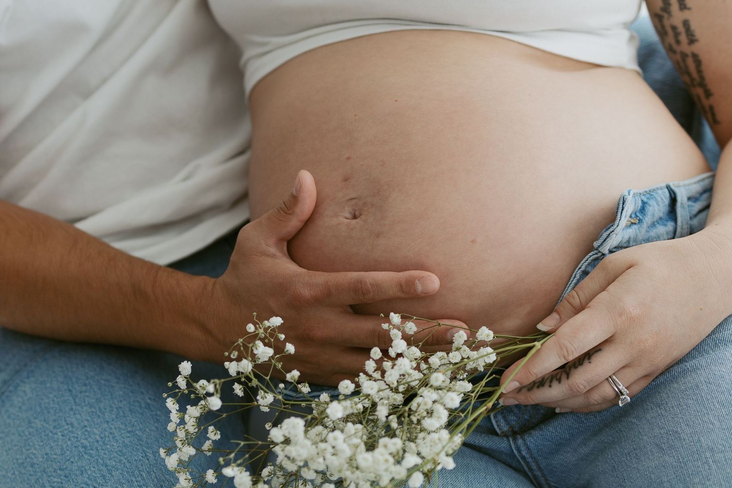 Pregnant belly with delicate baby's breath flowers creating a gentle maternity scene.