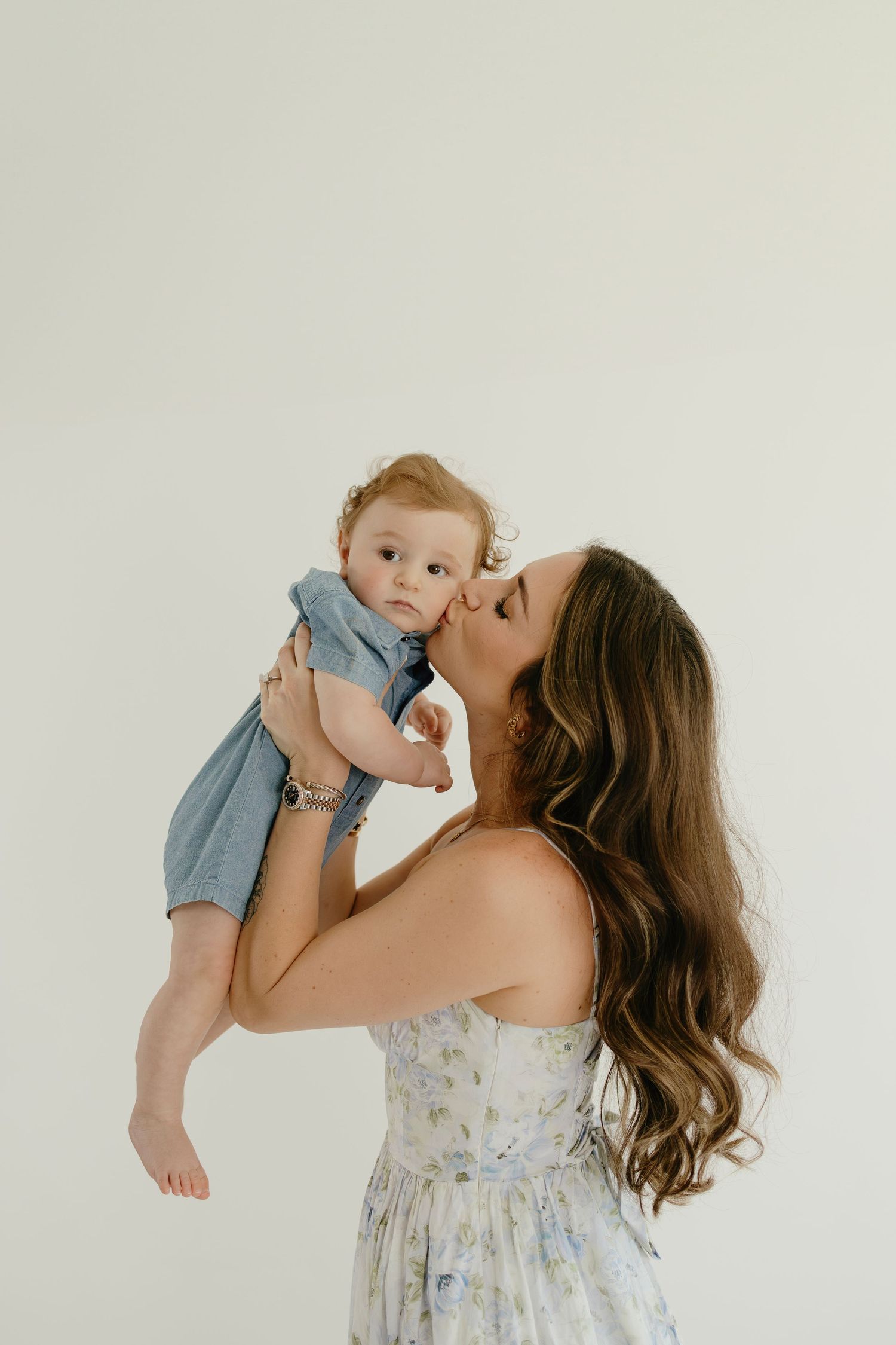 A tender moment between parent and baby wearing blue against a white backdrop.