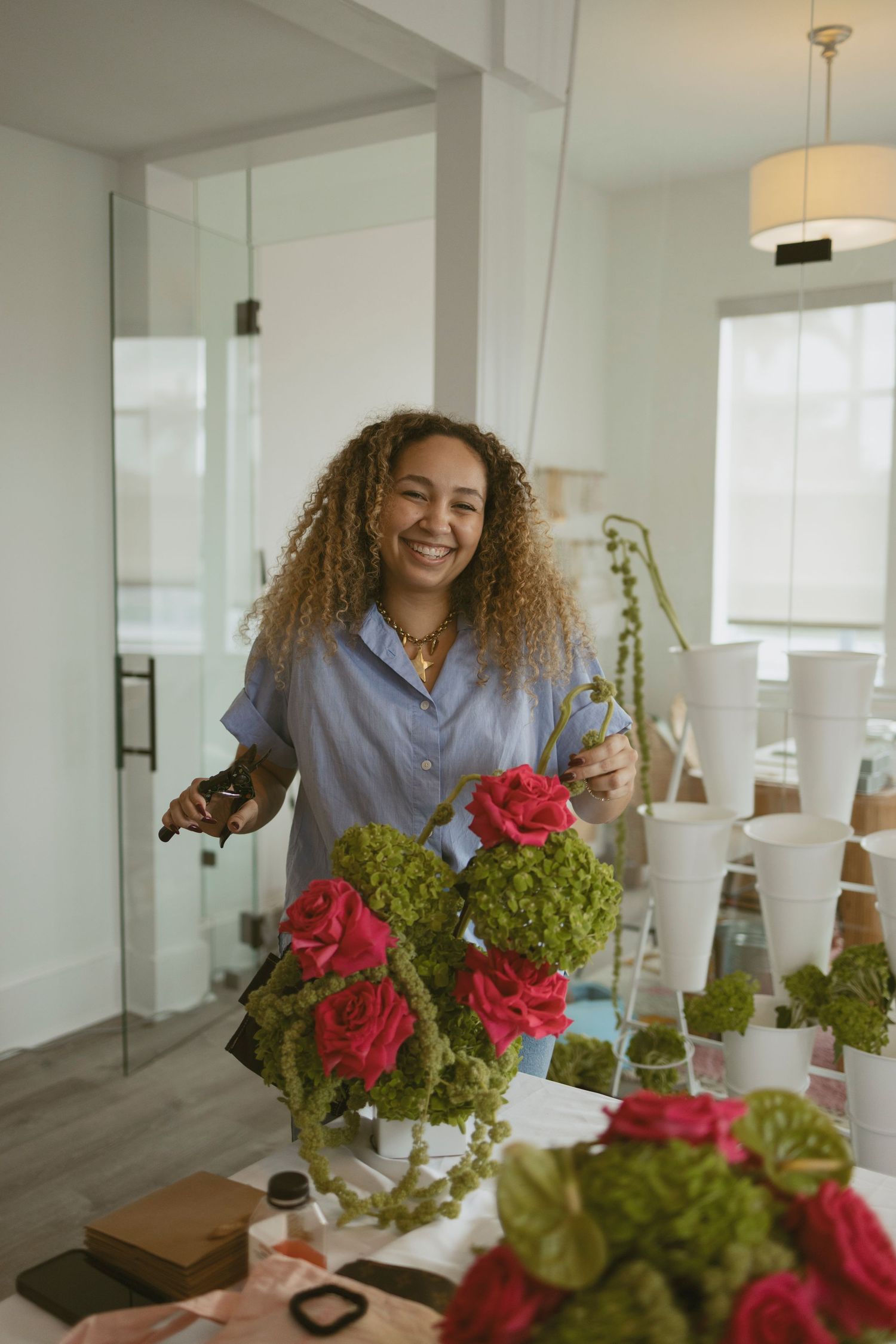 Person arranging vibrant red roses and green hydrangeas in bright modern indoor setting.