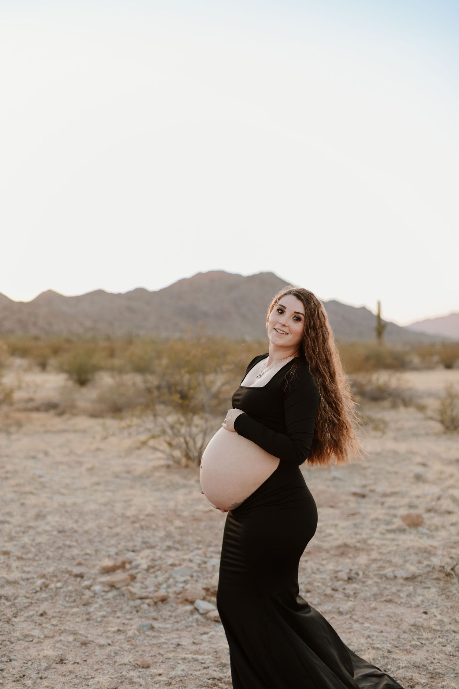 Outdoor maternity photo shoot near Phoenix with cactus and mountain views