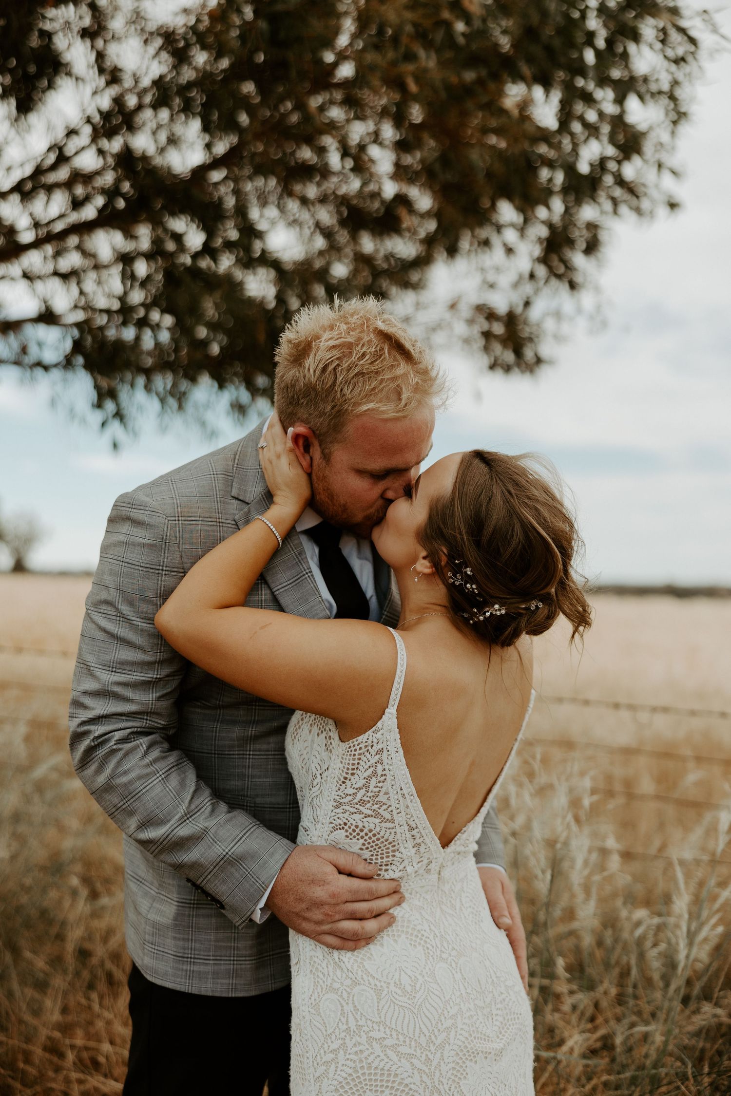 Intimate wedding portrait of couple embracing in a golden field at sunset.