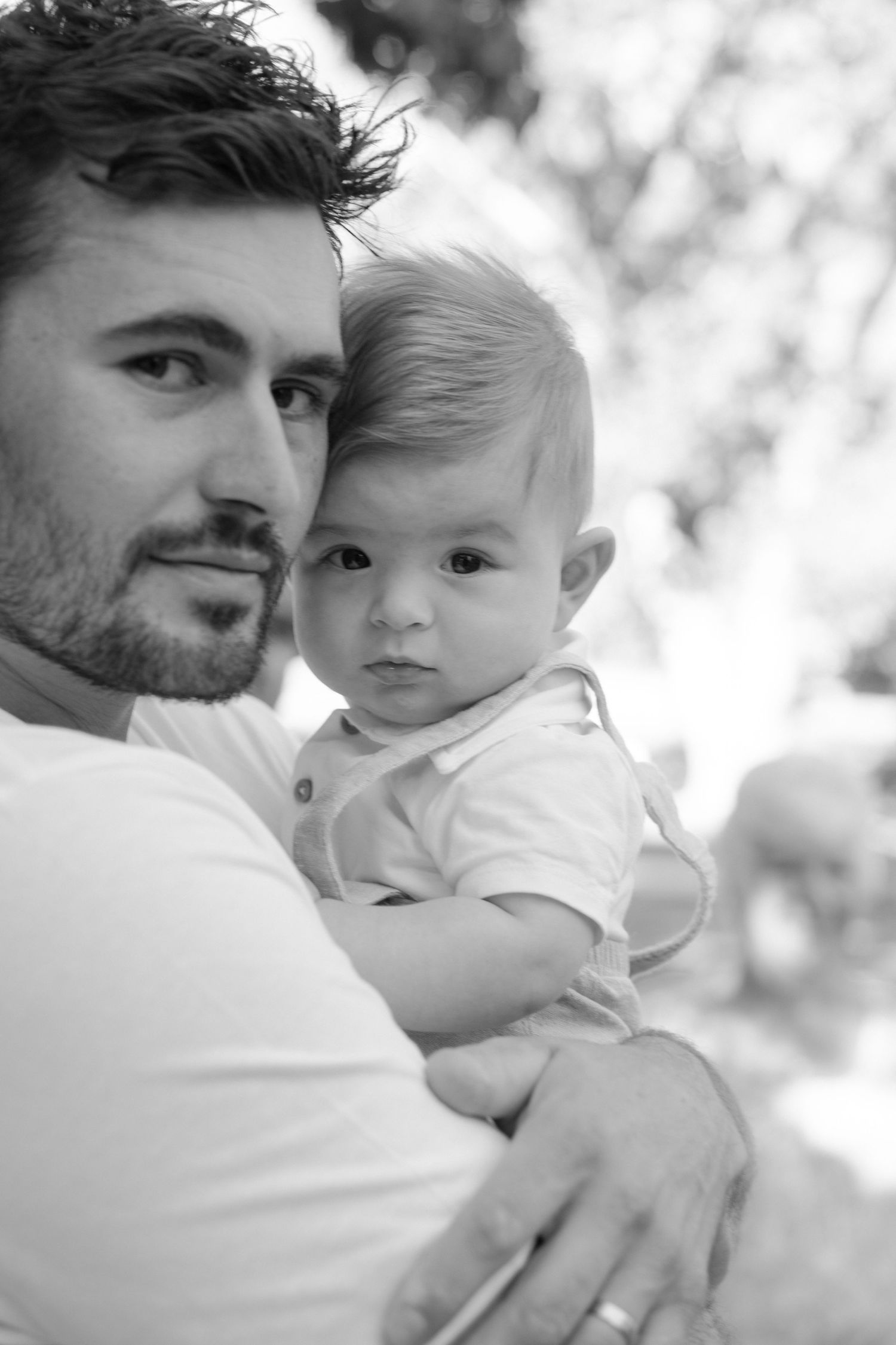 Black and white portrait of baby in white polo shirt being held.