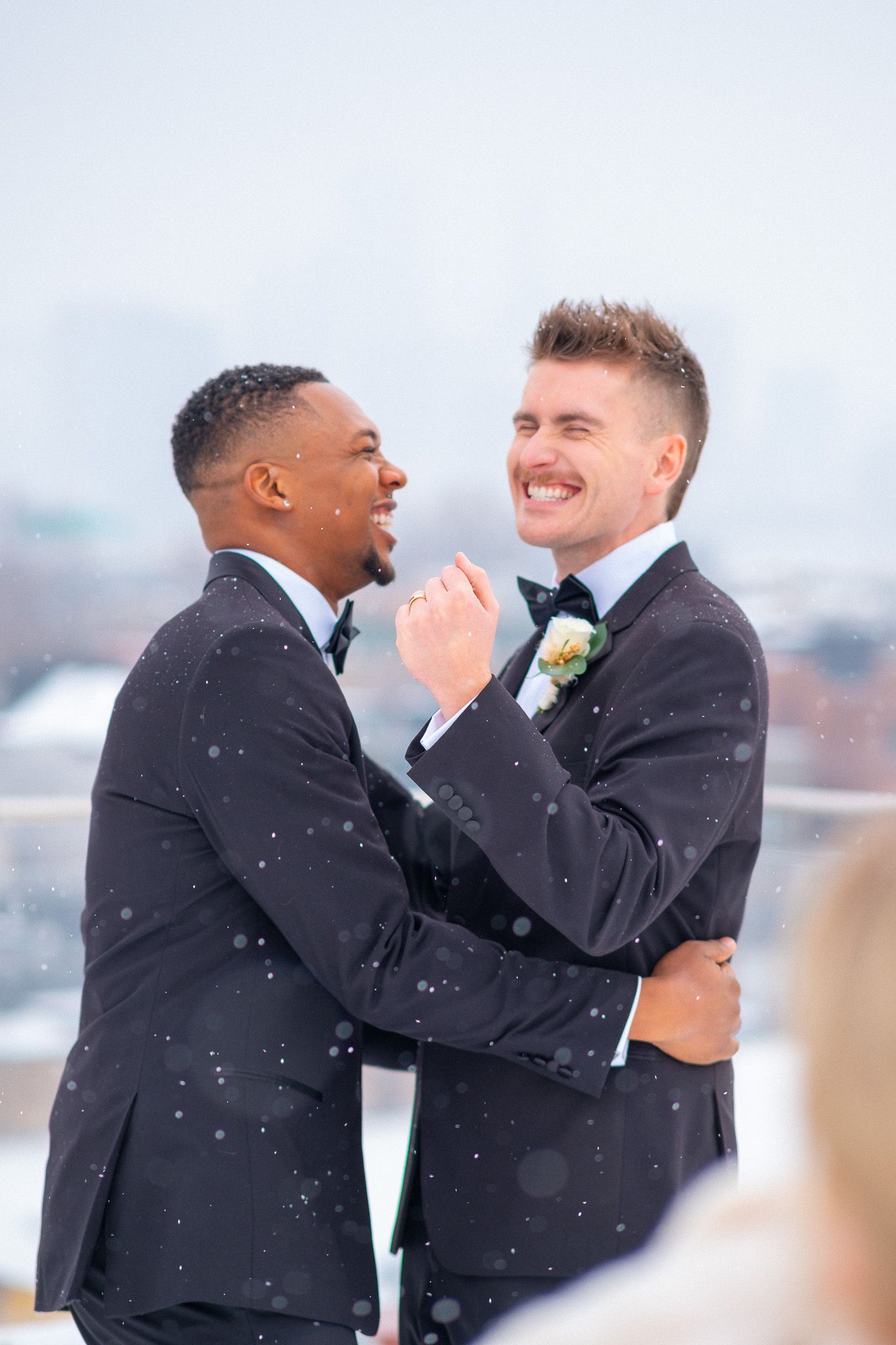 A gay couple celebrate their wedding while it snows on the roof of a wedding venue.