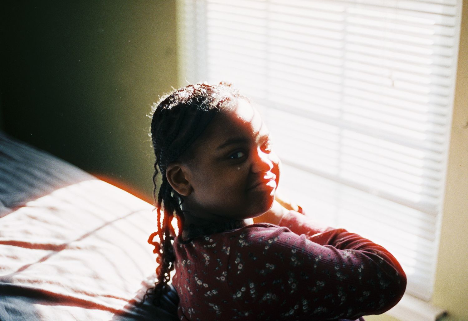 A portrait of a young girl looks over her shoulder at a window on 35mm film.