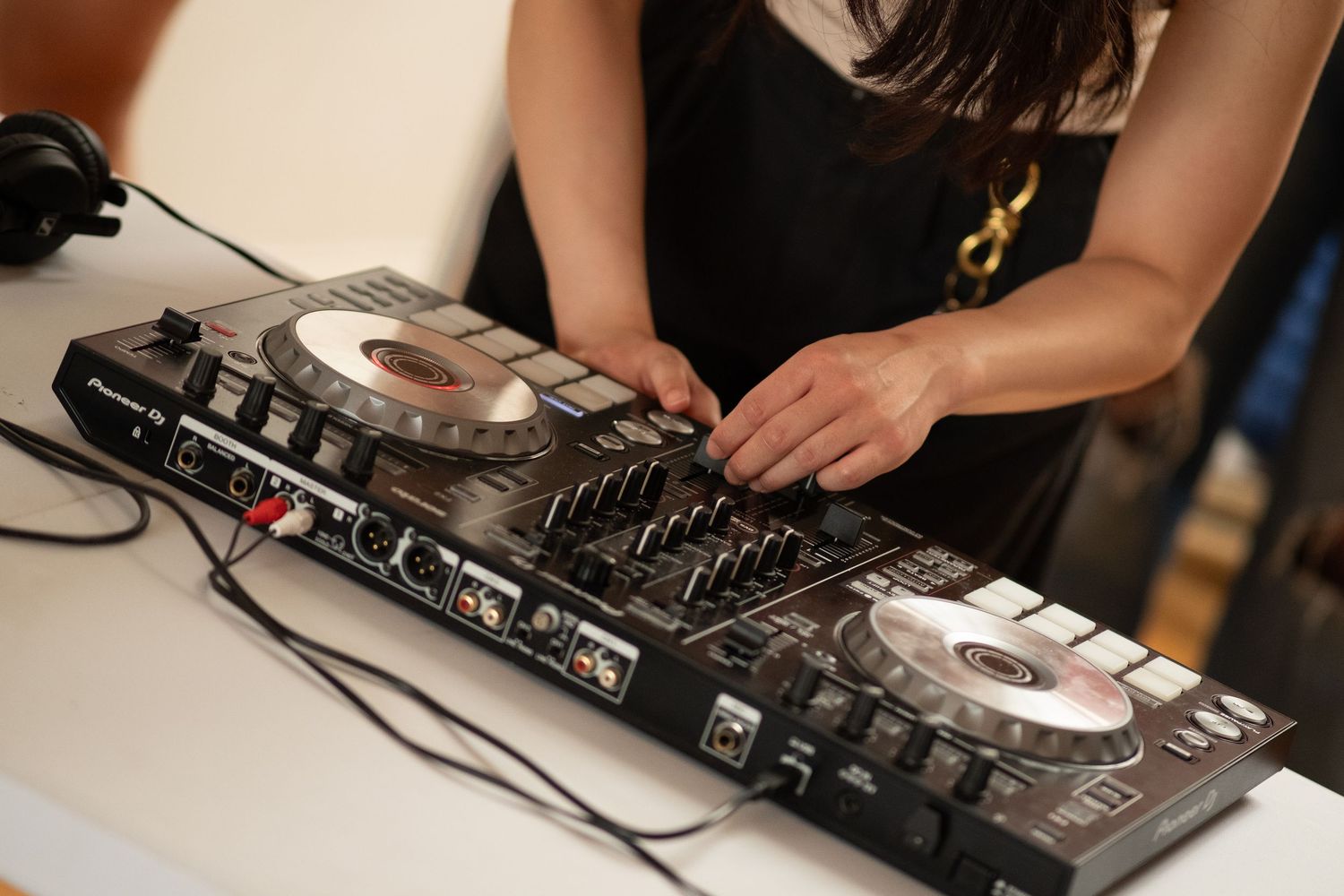 Hands hover over a DJ board at a community DJ event.