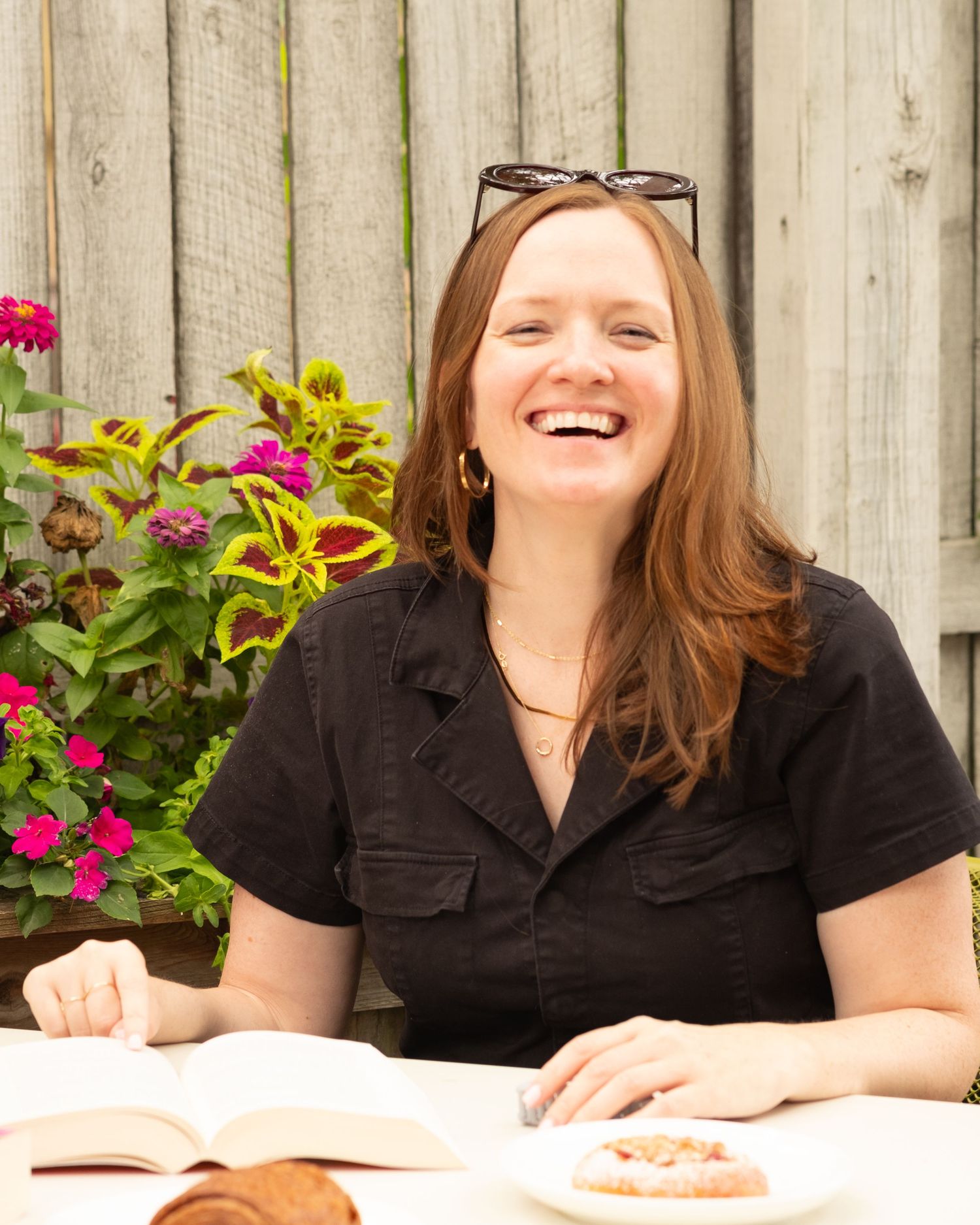 Outdoor personal brand image of a woman smiling with a book and a croissant.