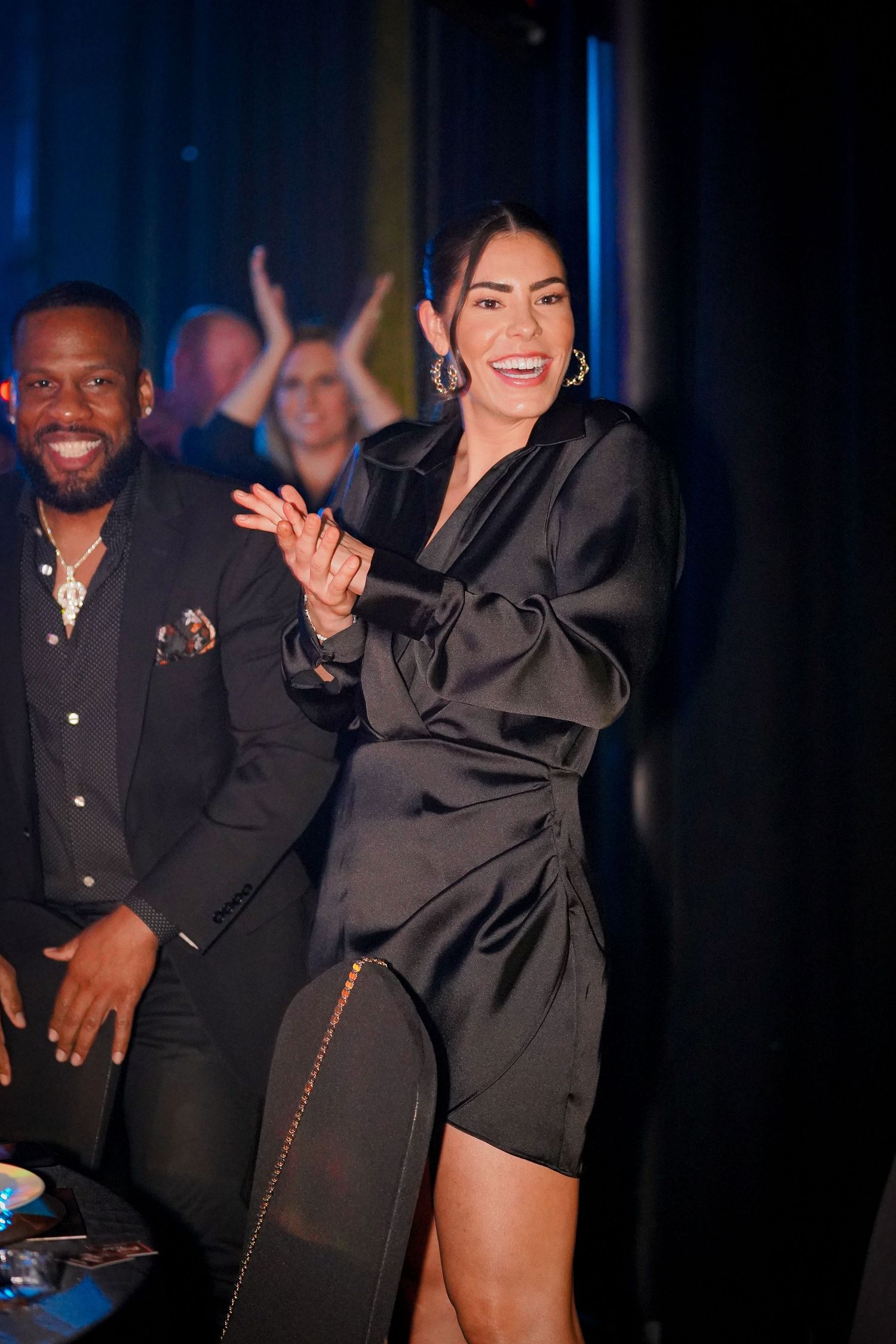 People in formal black attire enjoying and laughing during an evening event.