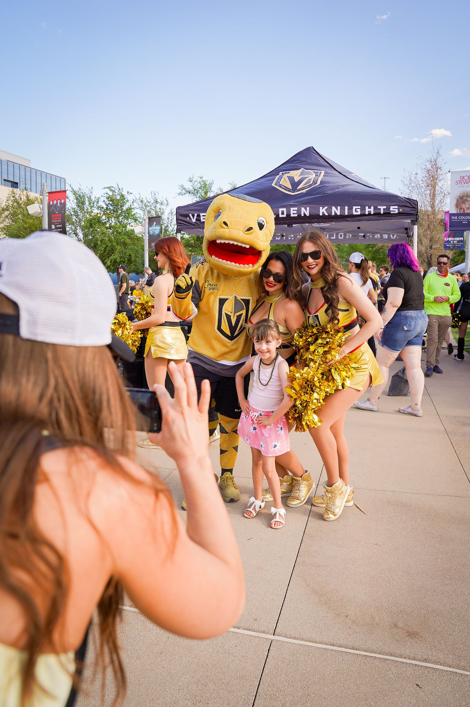 Vegas Golden Knights mascot poses with fans under Den Knights tent at community event.