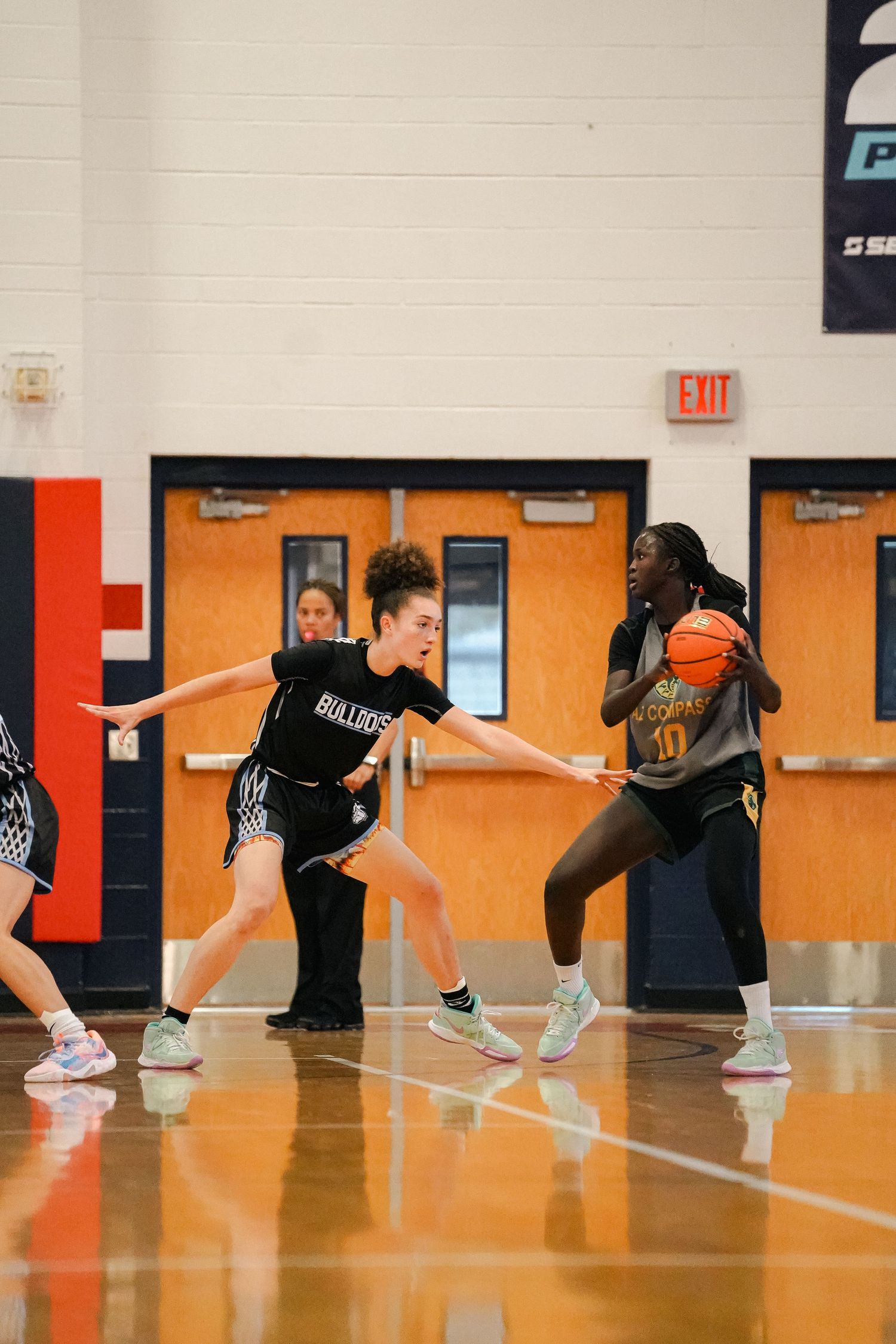 Basketball players compete for position during intense gameplay on indoor court.