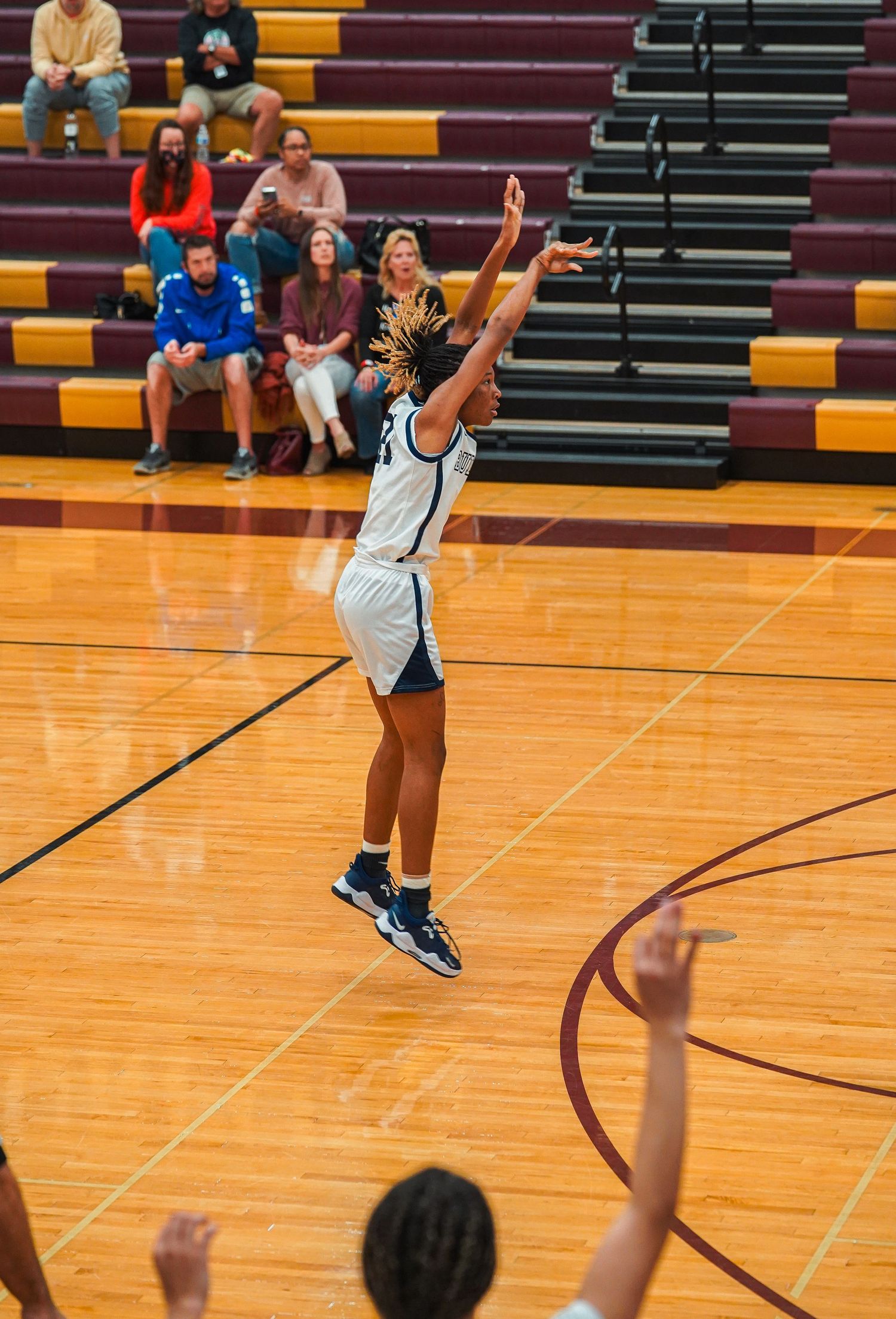Basketball player shoots free throw while spectators watch from bleachers.