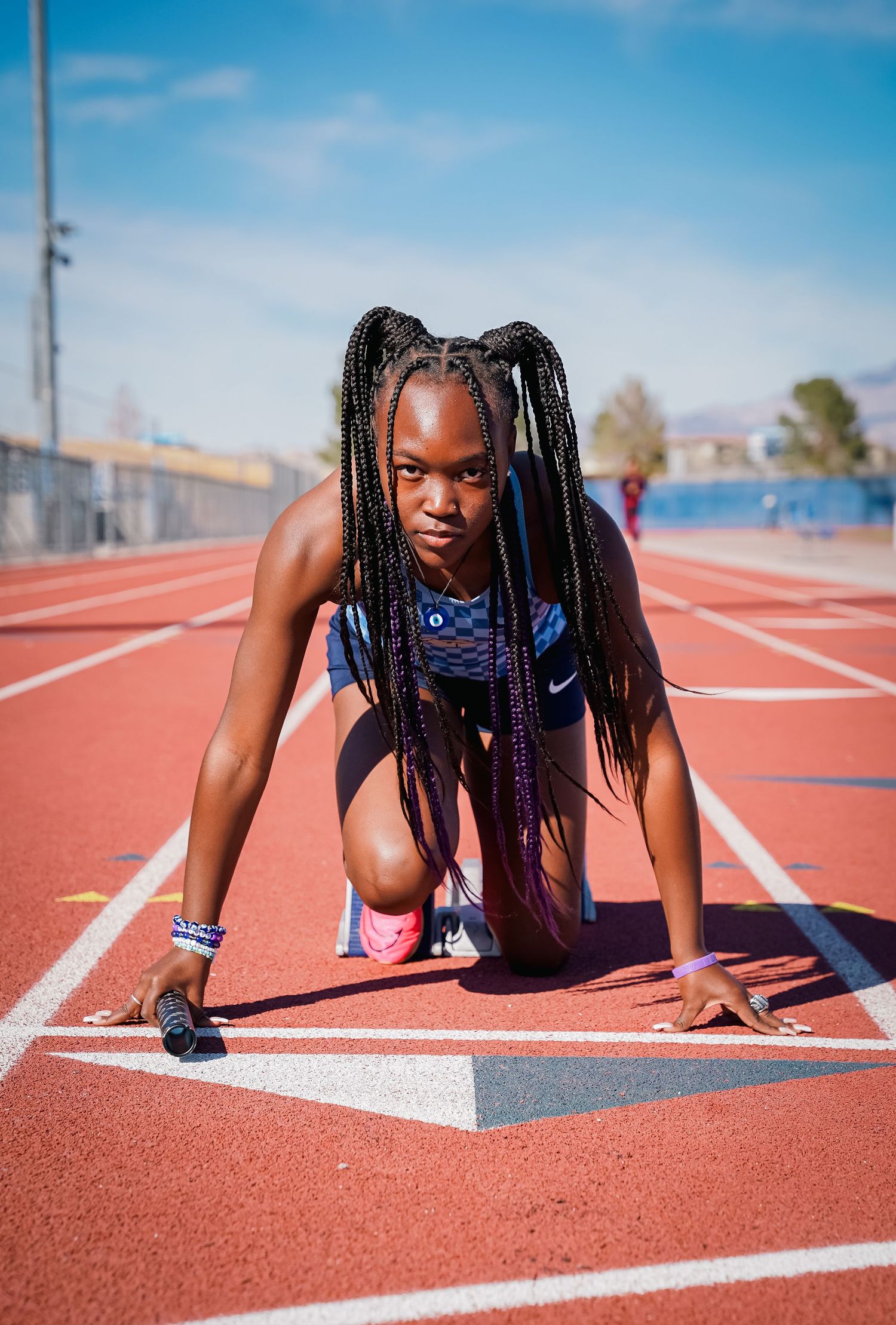 Athlete in starting position on red running track.