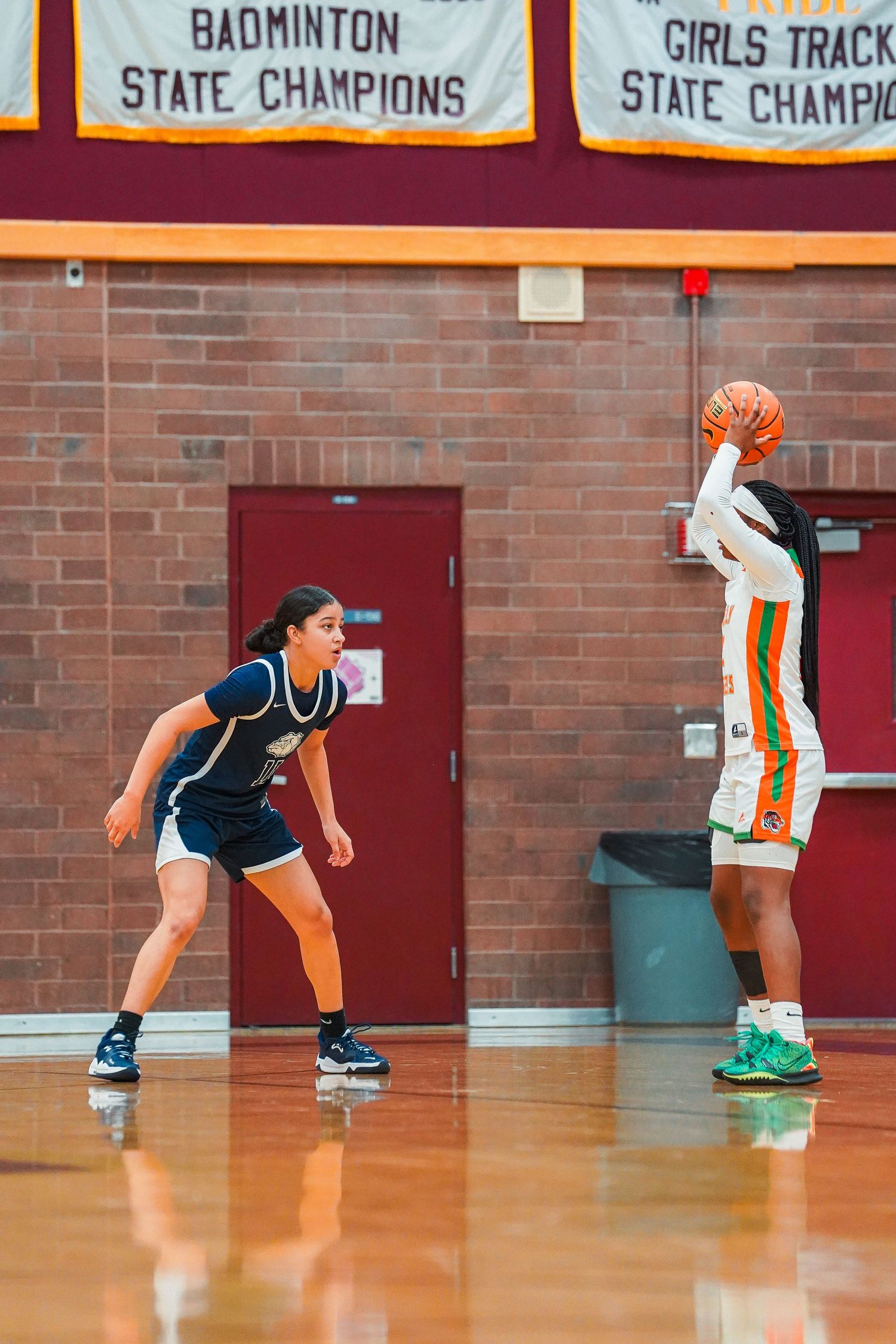 Players in athletic uniforms practice defensive stances under championship banners.