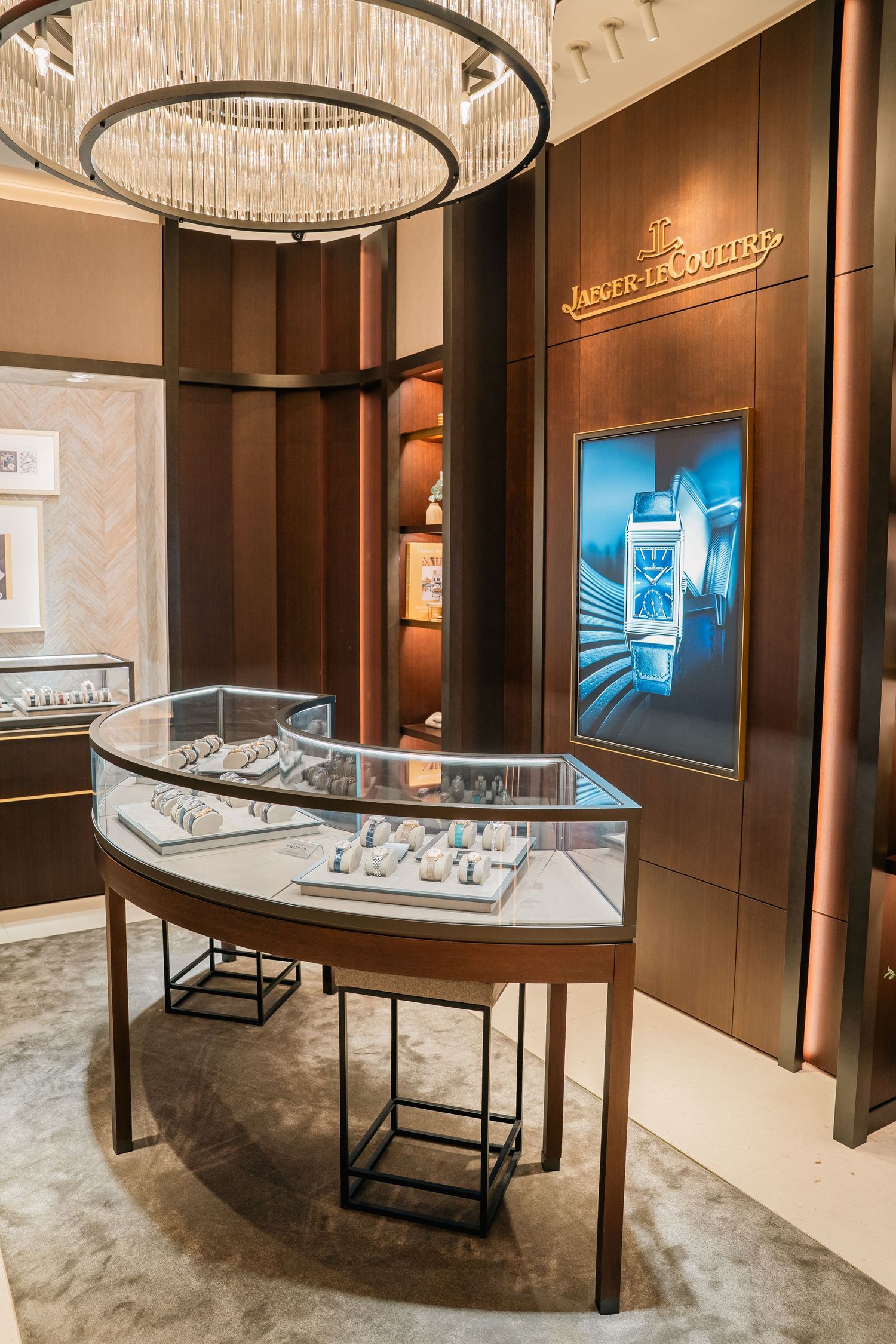 Luxury watch boutique with curved display cases and elegant circular chandeliers.