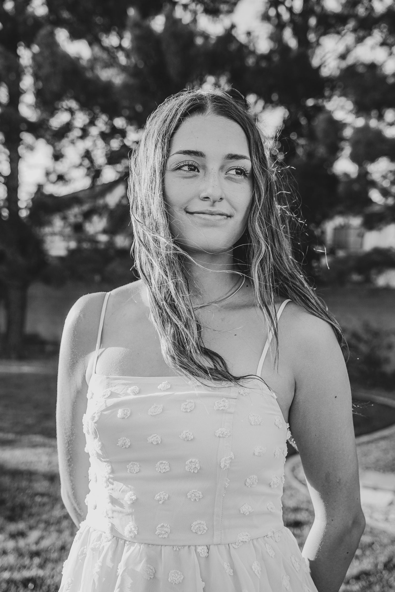 Natural black and white portrait of person in textured white dress with long hair.