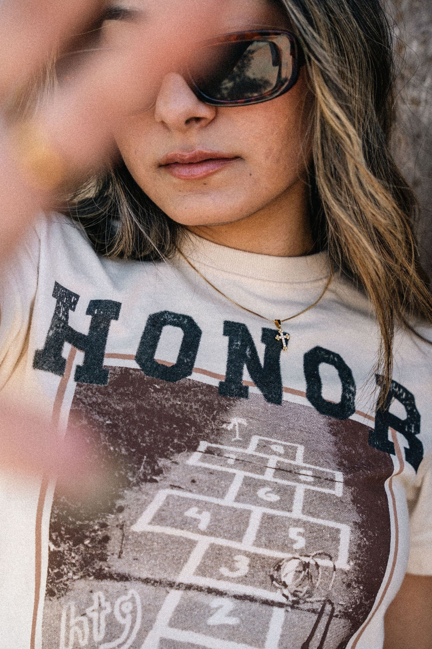 Close-up shot of a white Honor graphic t-shirt with a hopscotch design on the front.