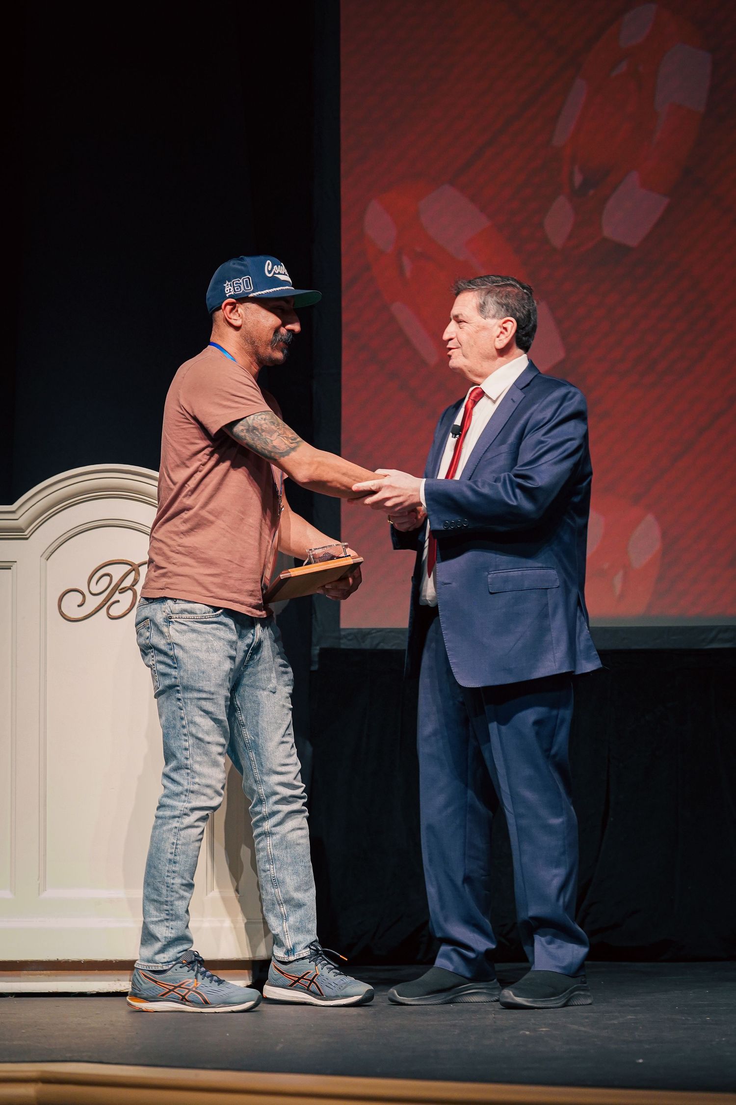 People interacting on stage during an award or recognition ceremony.