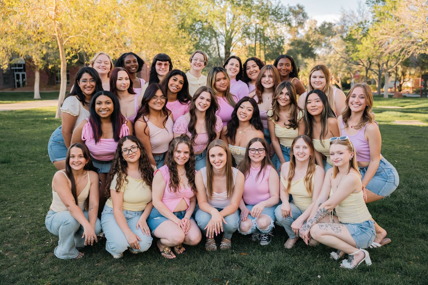 A large group poses together wearing matching pink and blue outfits on a grassy lawn.