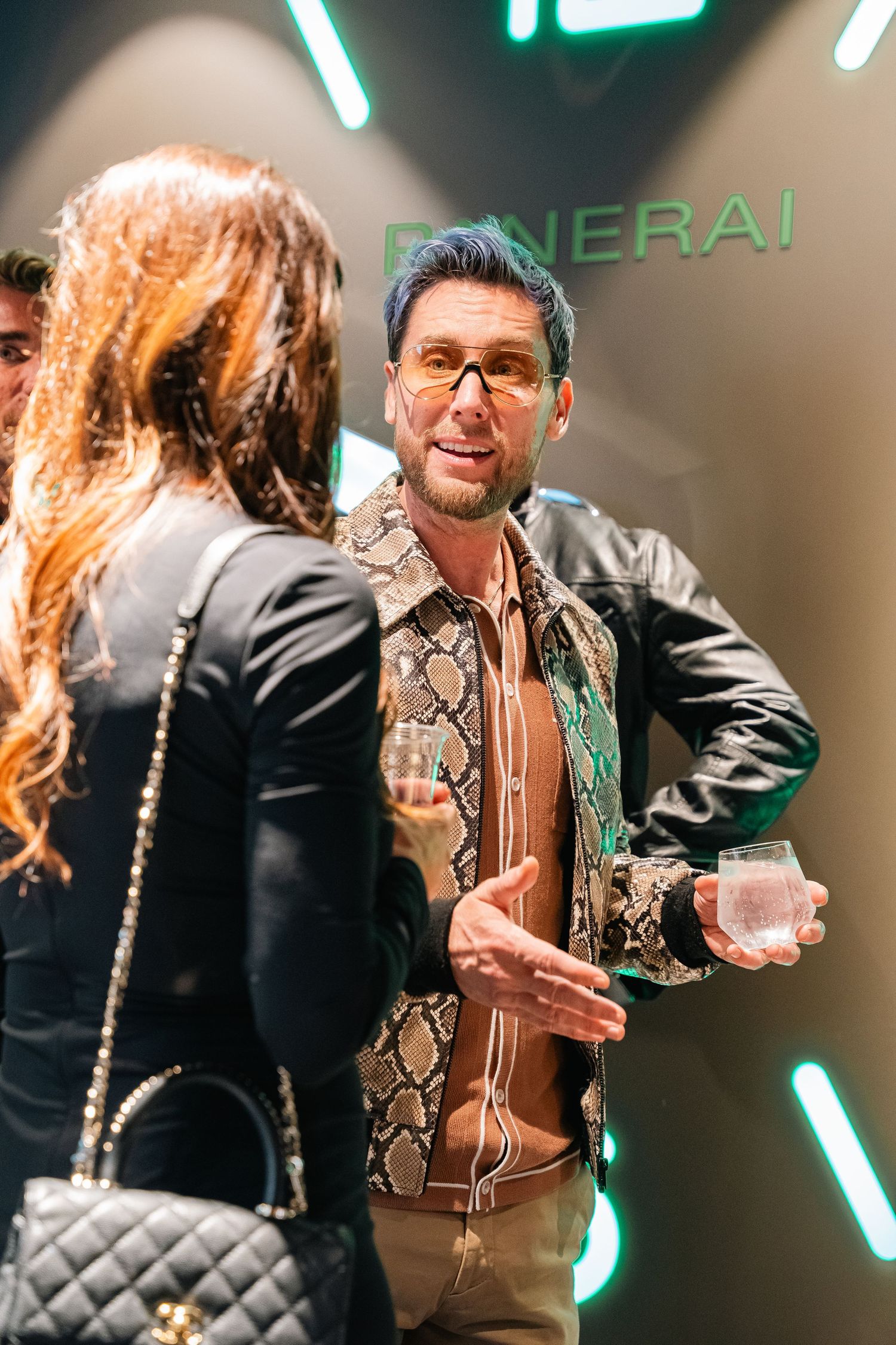 Social gathering at luxury retail event with neon lighting.