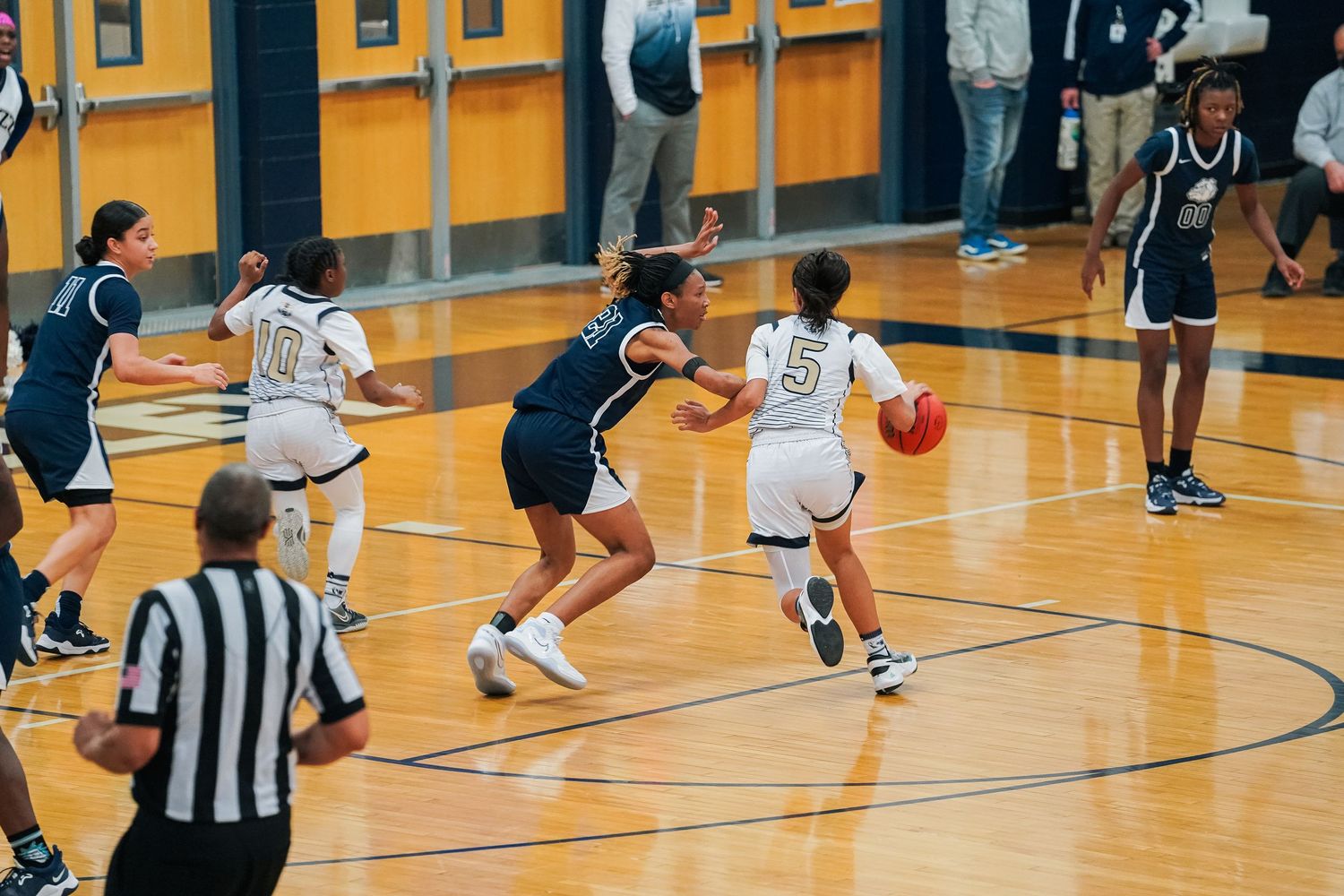 Basketball players compete on a bright gymnasium court during a game.